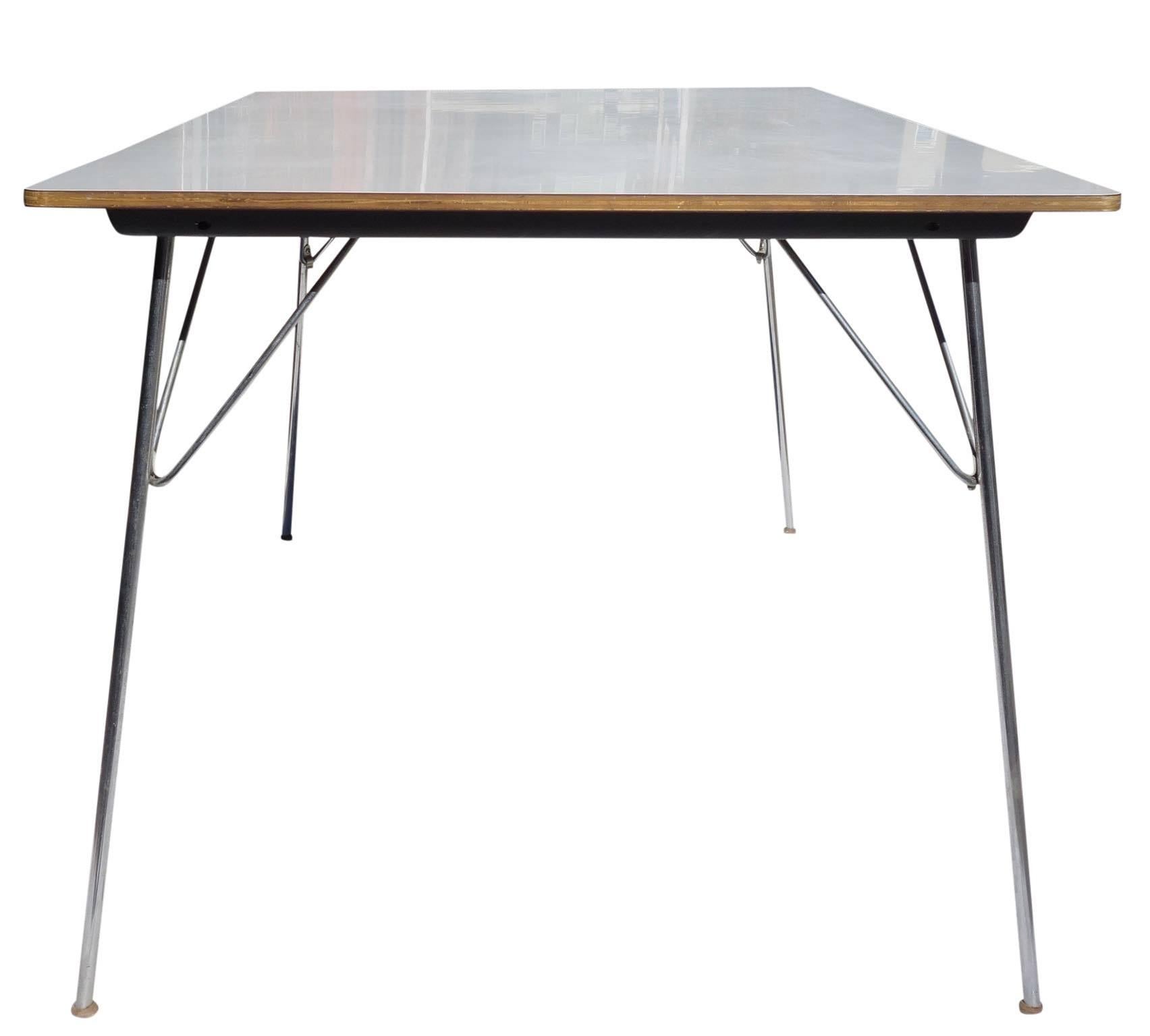 Wonderful example and highly function dining table by Charles and Ray Eames for Herman Miller, 1954. Rectangular white laminate on birch top with folding chromed steel legs. All feet are present. Straps and label intact.