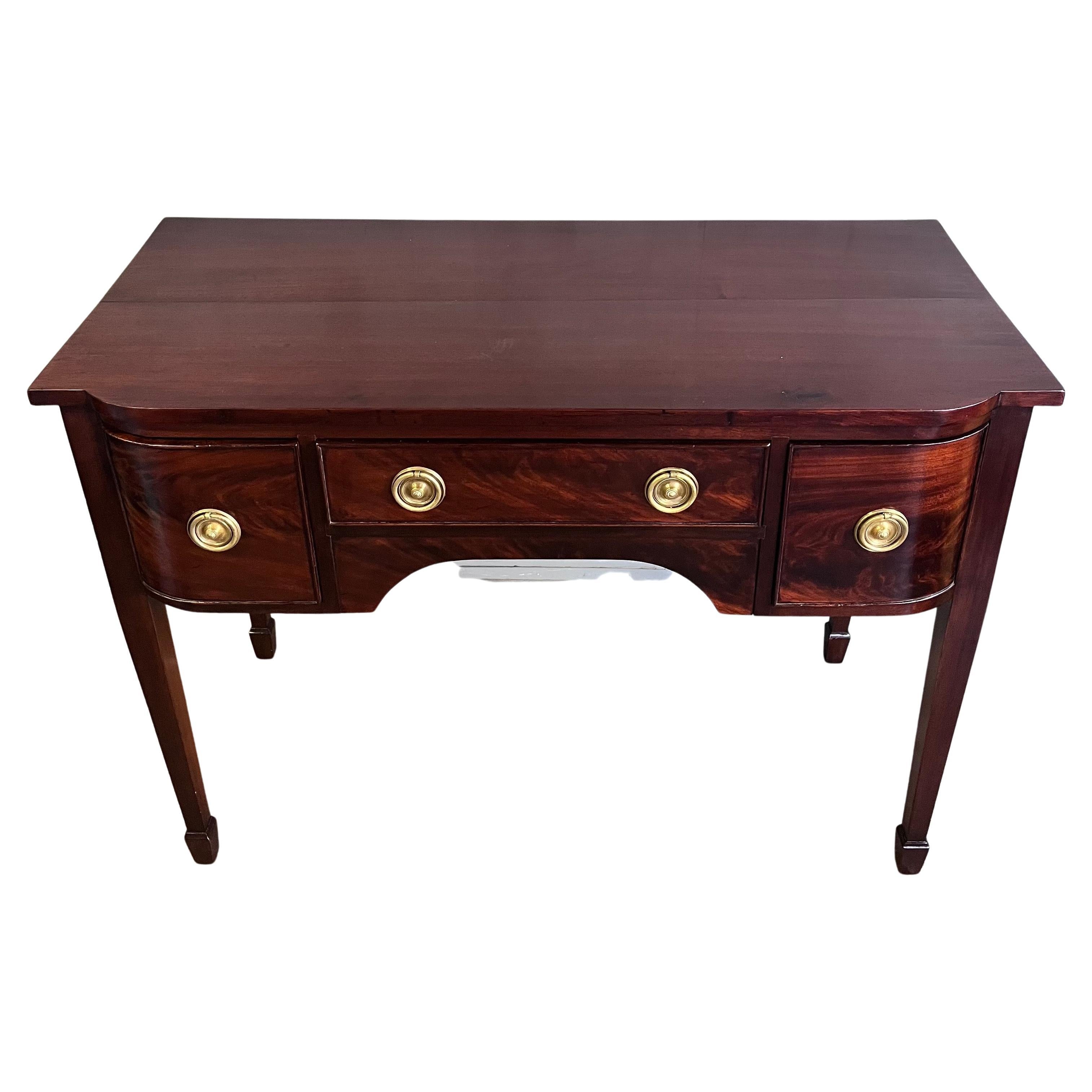 Georgian Hondurian mahogany bow front sideboard and server. Beautiful dark brown color with an old surface. Strong brass ring pull hardware. Tall Hepplewhite legs terminating on spade feet. Good medium scale with balance and proportion. A middle