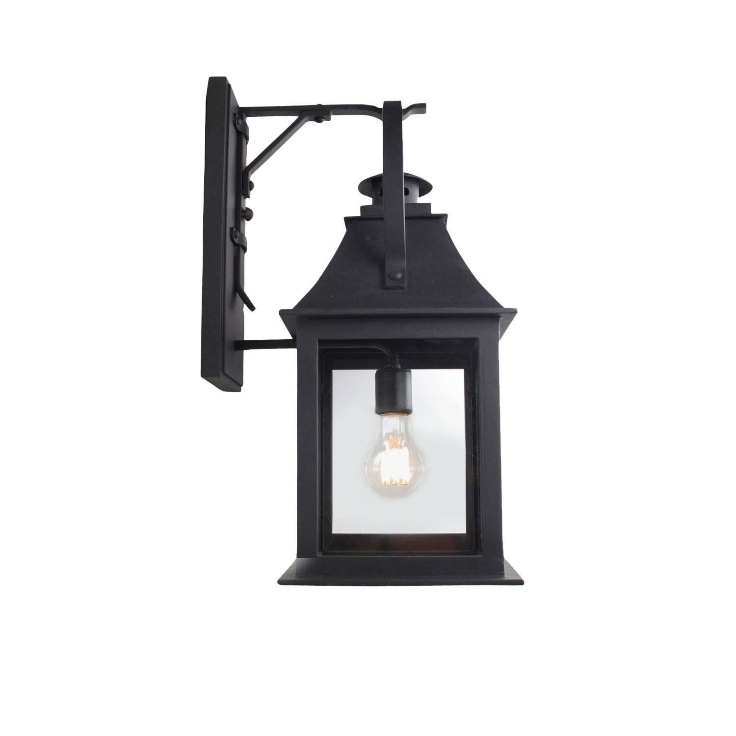 This lantern references both old and new with Classic features including a stove pipe top and oversized hoop, juxtaposed with modern lines and open glass panels. Hand-forged in heavy gauge iron.

Backplate dimensions (inches): 5 W x 12 H
Lantern