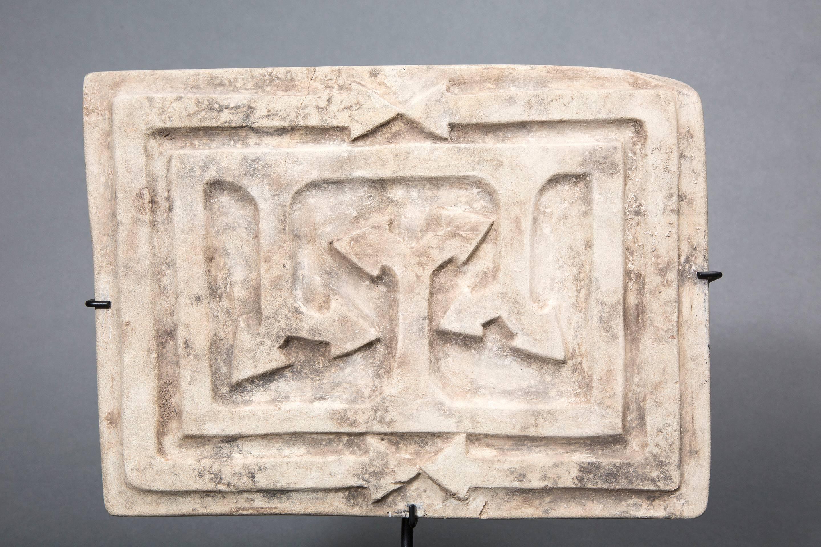 Rectangular engraved stone whose design represents an area bounded by lines and arrows. The symbolic meaning of these mysterious objects remains difficult to decode. They probably were divinatory instruments based partly on astrology.
When they