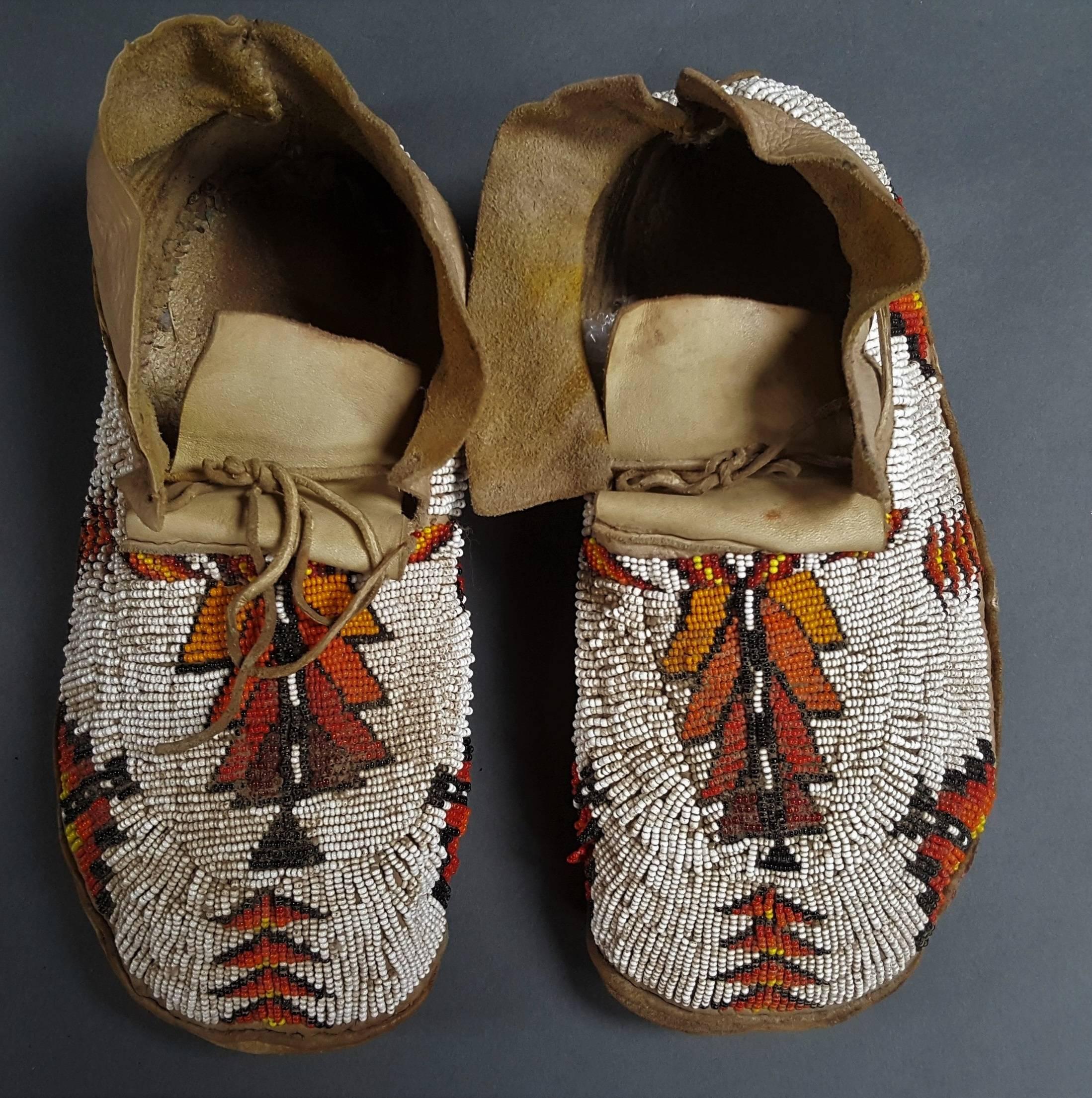Pair of moccasins. Plains Indians, USA, 20th century.
Pair of leather moccasins and milking beads, age patina.

Dimension: 28 X 11 cm
Dimension with stand: 39 x 27 x 10 cm.
 