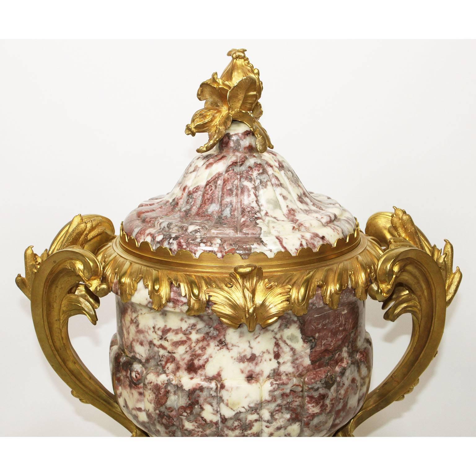 A very fine French 19th-20th century Louis XV style ormolu-mounted Fleur de Pêcher marble vase or urn with a gadrooned cover surmounted by a pomegranate finial, above a tapering ovoid body applied with a pair of scrolled handles cast with