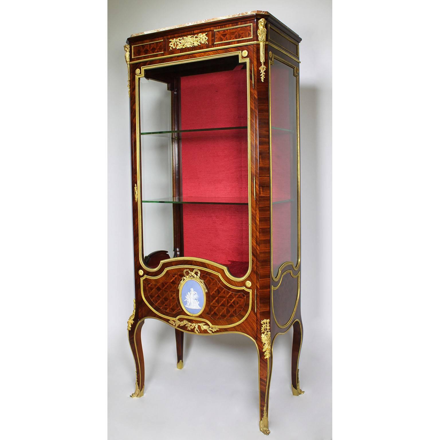 A very fine French Louis XV style ormolu and jasperware-mounted mahogany single door vitrine, attributed to François Linke (1855-1946). The two upper front corners surmounted with ormolu figures of females and centred with an ormolu allegrical