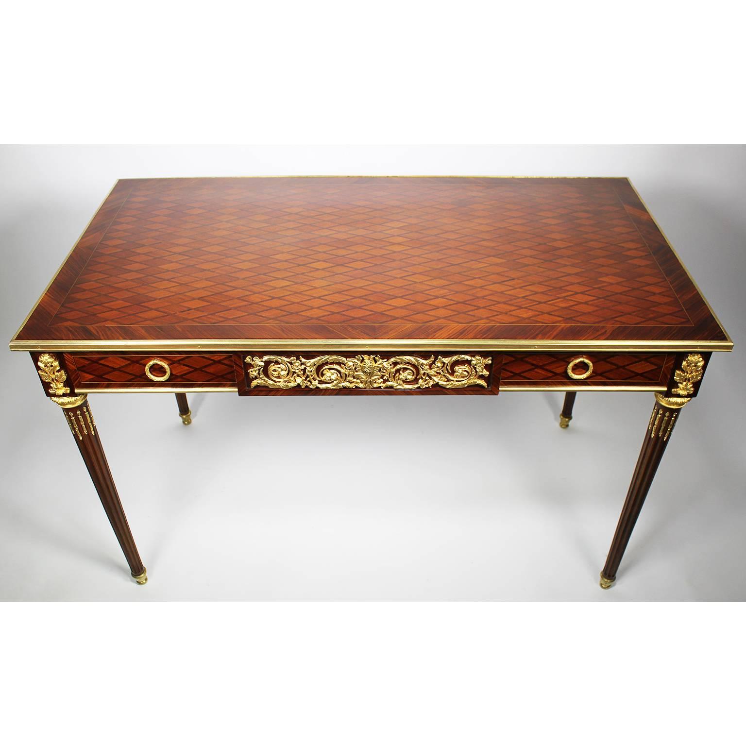 Raffinato tavolino da salotto francese del XIX-XX secolo in stile Luigi XVI con parquet e ormolatura, il corpo è circondato da modanature in bronzo. Il grembiule ripete il motivo del parquet ed è dotato di un cassetto con decorazioni in bronzo