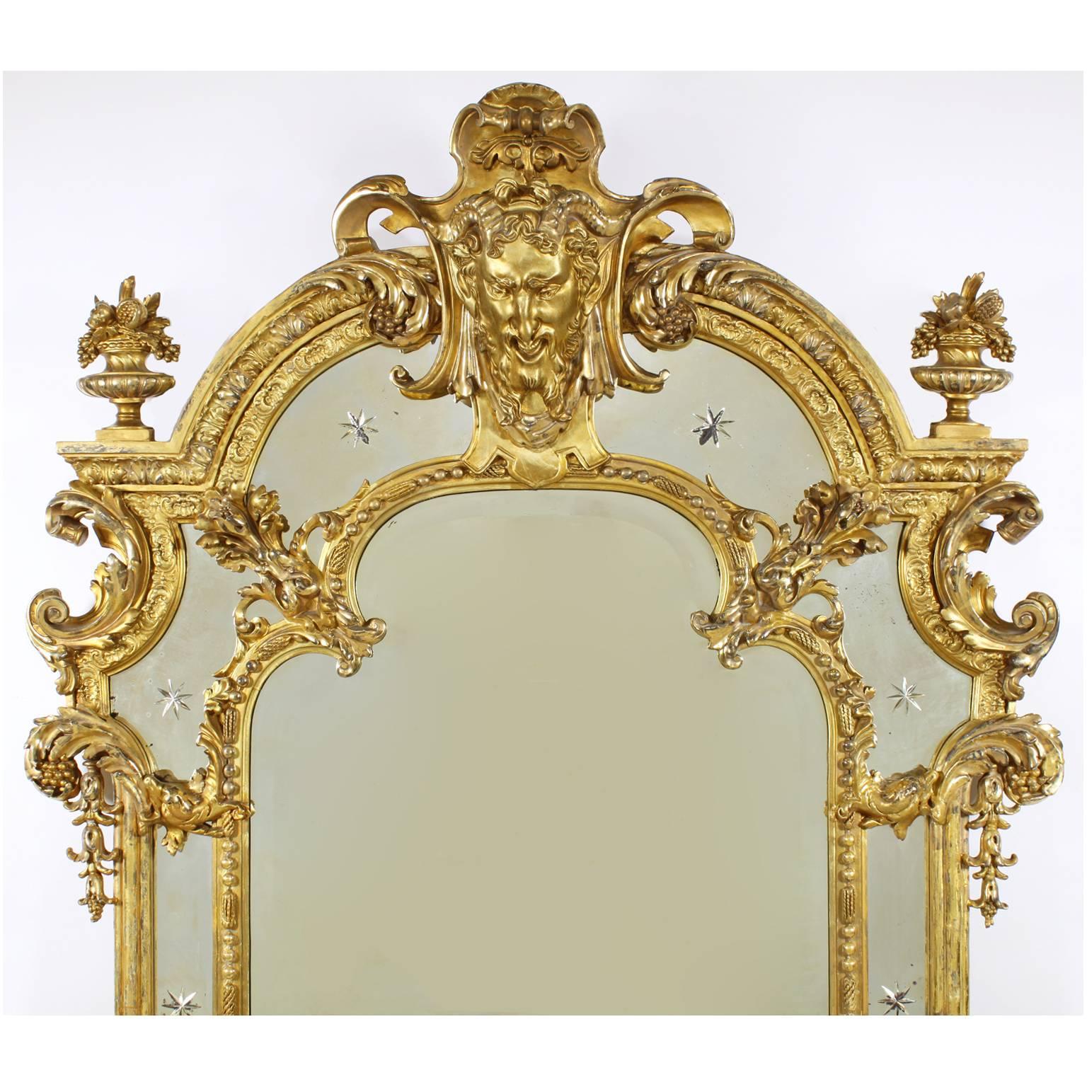 A very fine French 19th century Louis XV style giltwood and gesso carved figural mirror frame, Surmounted with two cherubs amongst fruits and vines, each holding the entire frame one on each side, the top with a mask of a satyr surmounted with