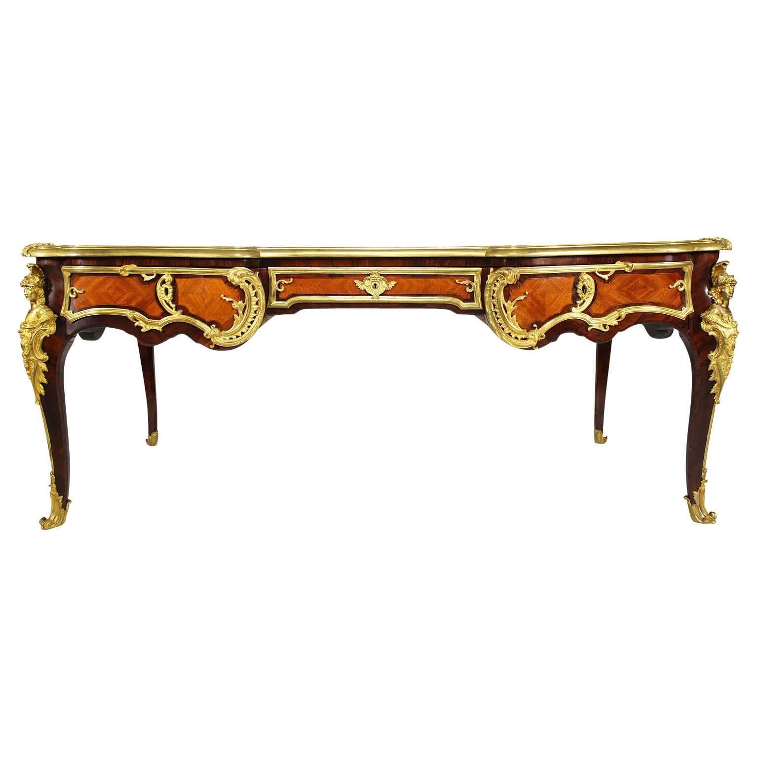 A very fine and large French 19th century Louis XV style gilt bronze-mounted kingwood and walnut bureau plat by H. Conquet after a model by Charles Cressent. The shaped rectangular top inset with a tooled leather writing panel and fitted with three