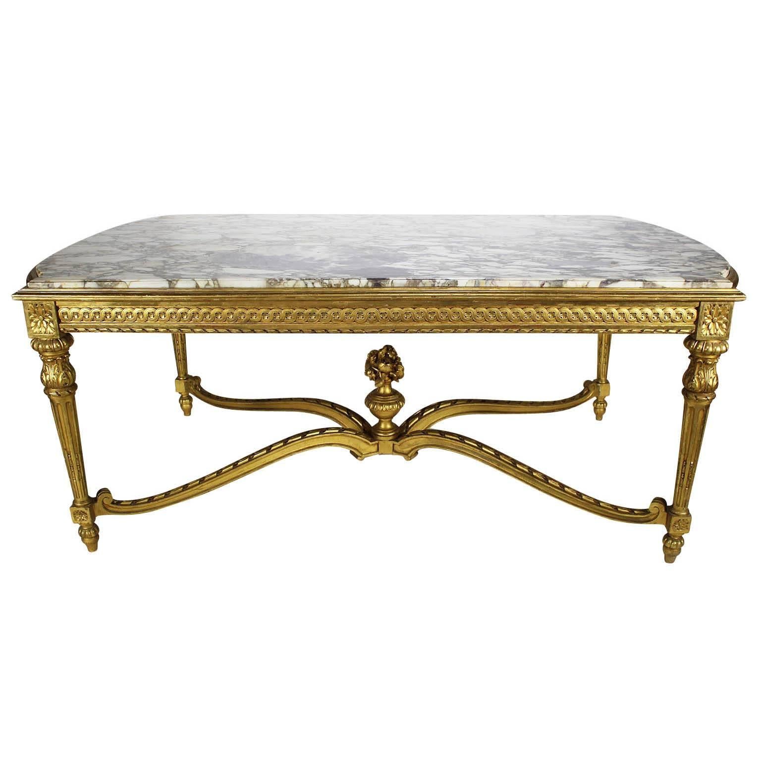 A very fine and large French 19th century Louis XVI style giltwood carved center hall table with marble top. The rectangular shaped top with rounded ends, fitted with a Brêche Violette marble top, raised on four fluted legs conjoined with an 