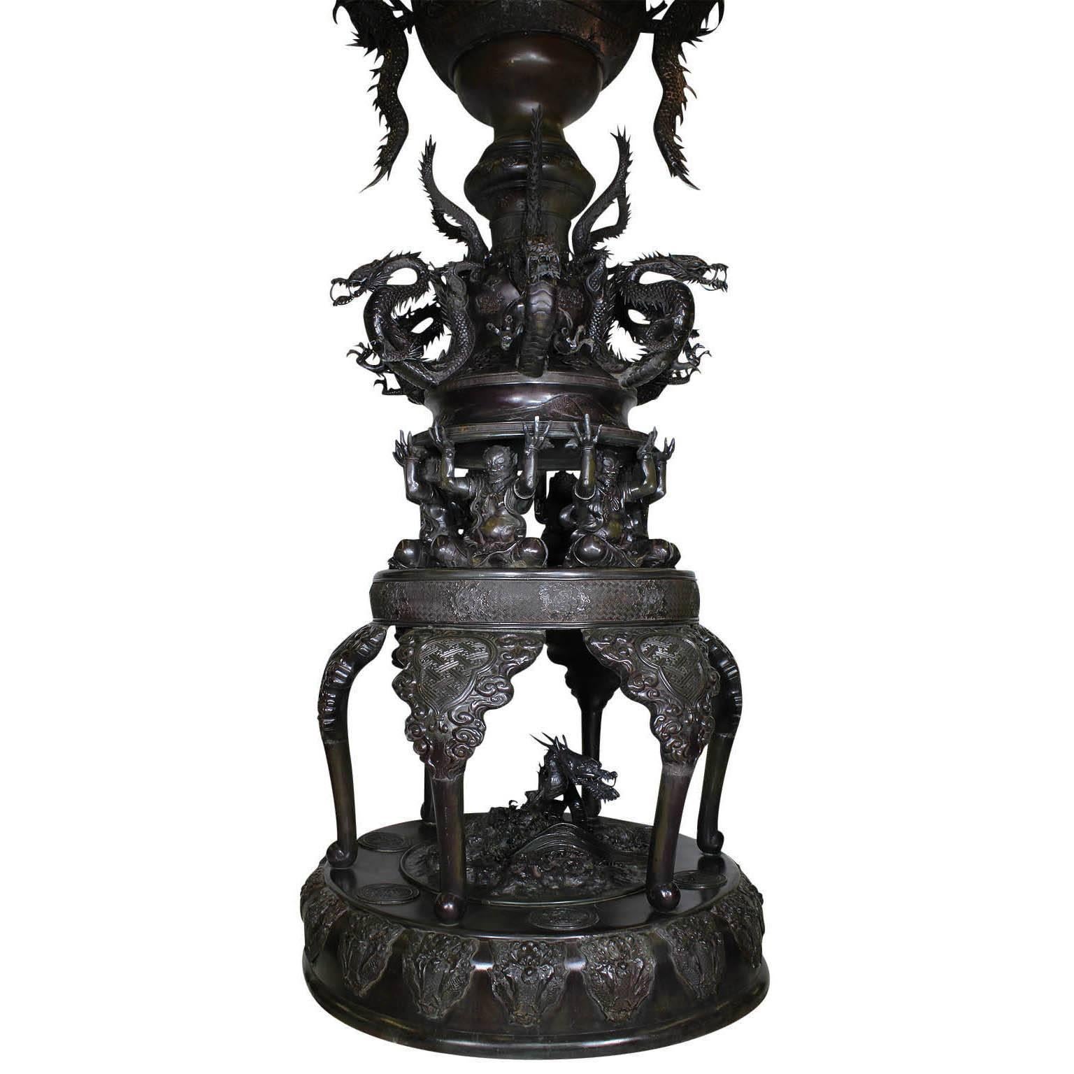 Monumentale japanische Bronze-Urne aus der Meiji-Periode, aufwändiges, mehrteiliges Ausstellungsstück mit großen, hochreliefierten Drachen-'Henkeln' zu beiden Seiten des eiförmigen Körpers mit zwei geformten Reserven einer auf einem Drachen oder