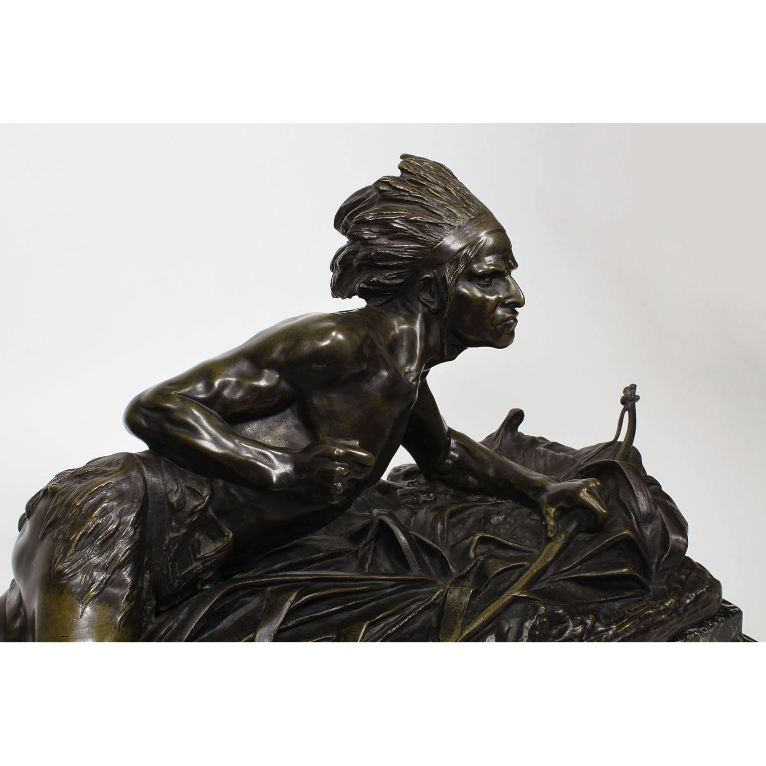 A very fine French, 19th century Patinated bronze group of a Crouching Native American Indian on the lookout, in a dark brown patina and raised on a veined green marble base, by Edouard Drouot (French, 1859-1945). Signed: E. Drouot. The back with