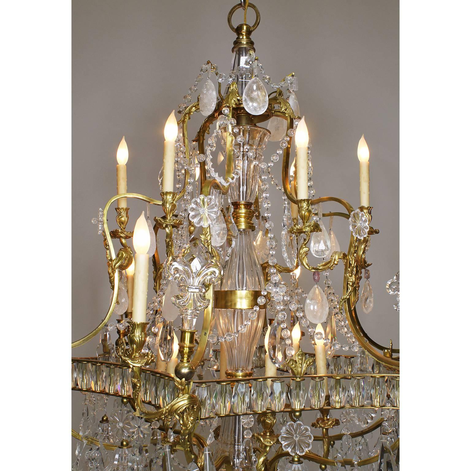 A large fine French Louis XV style gilt bronze rock crystal, amethyst, crystal and cut-glass sixteen-light chandelier in the manner of Baccarat. The floral gilt bronze frame decorated with fleur de lis, a wide central cut-glass stem, all surmounted