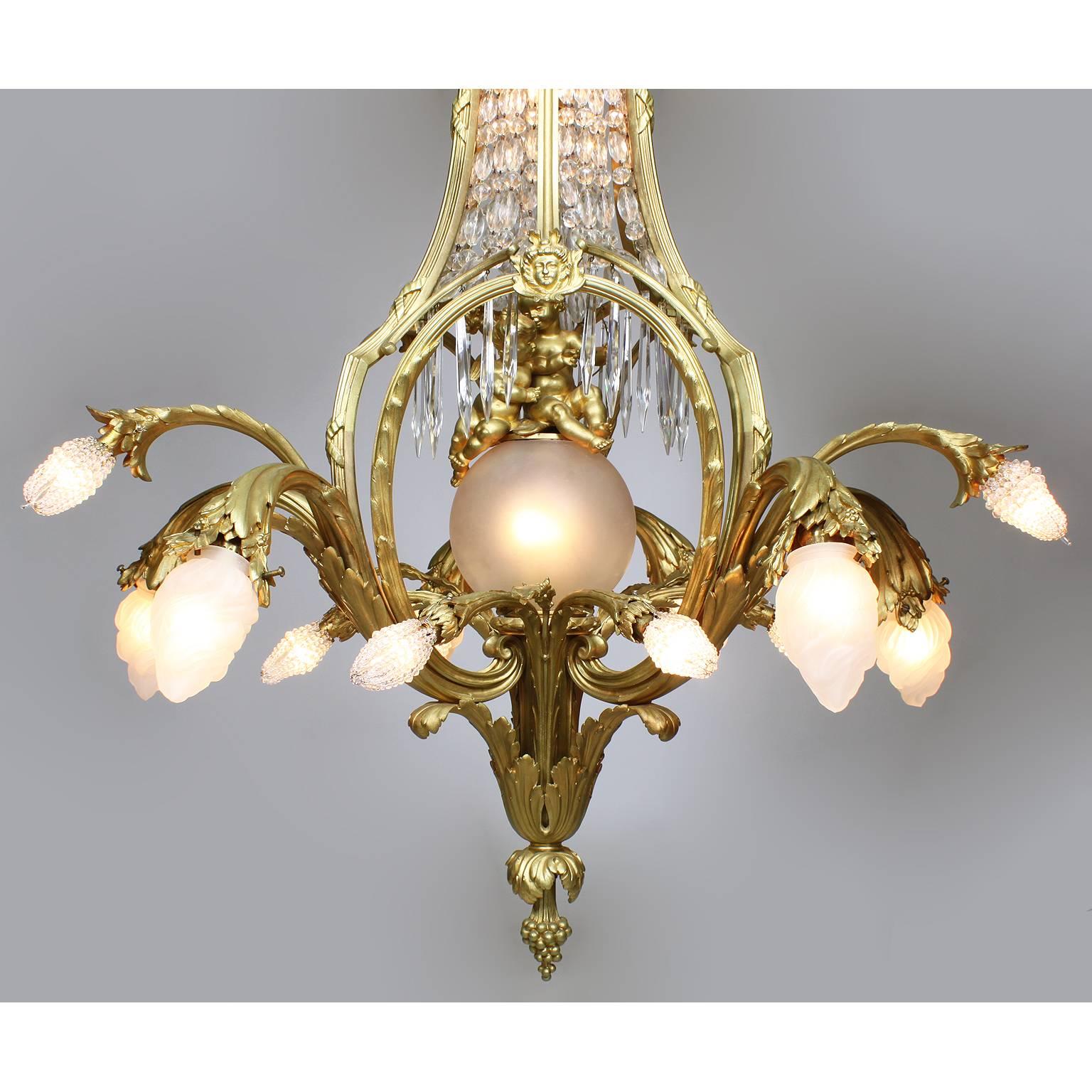 A large and rare French Belle Époque gilt bronze and cut-glass twenty-four light figural chandelier. The elongated gilt bronze frame with scrolled floral arms protruding from the lower section with frosted glass shades and beaded glass bulb covers;