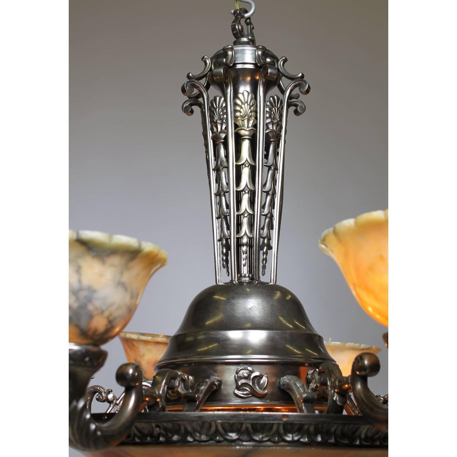 A French early 20th century Art-Deco silvered bronze and carved caramel-colored alabaster eight-light chandelier. The intricate pierced floral strand cone-shaped stem supporting a circular plateau surmounted with eight scrolled cornucopia
