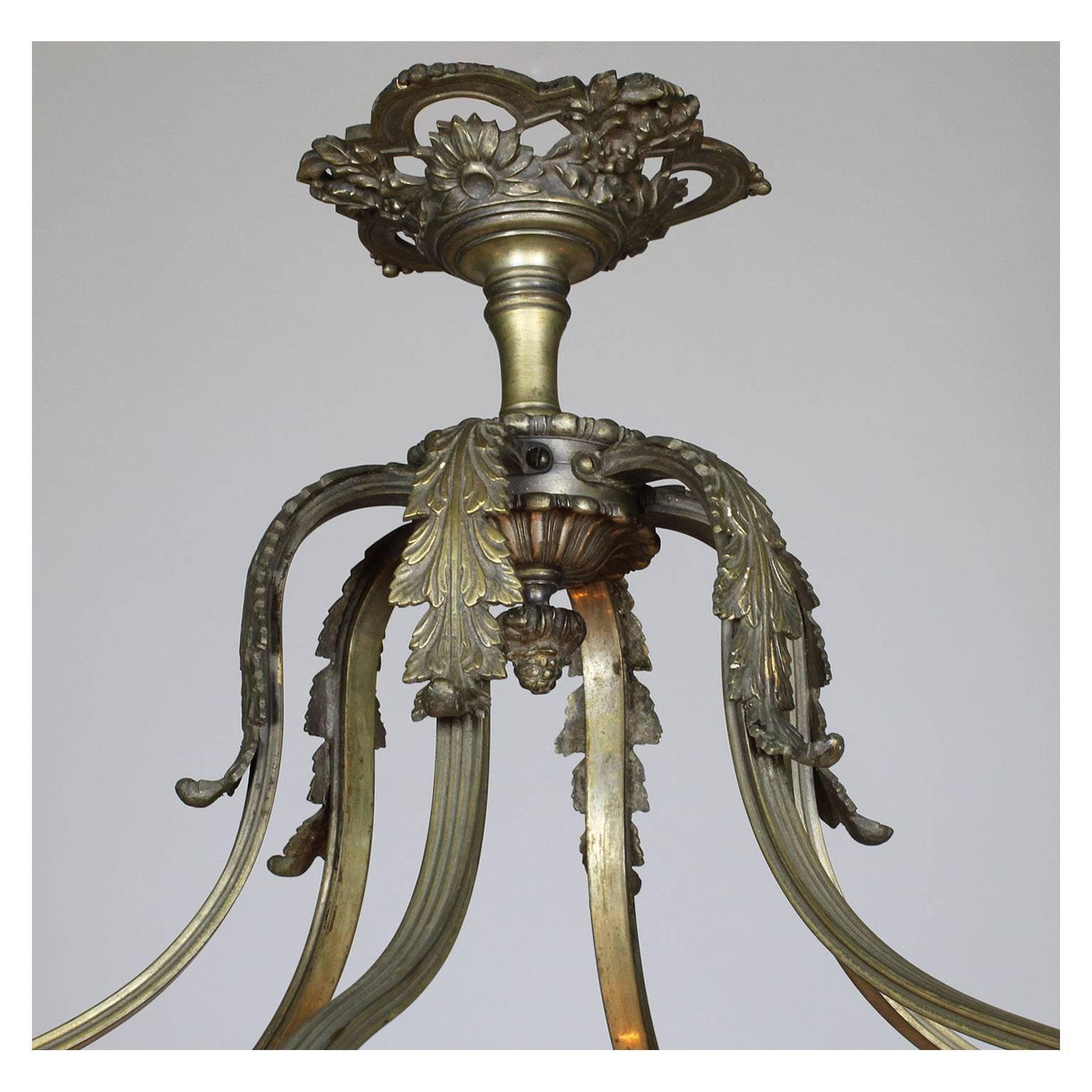 A French early 20th century Art Deco and silvered bronze carved veined ivory-colored alabaster six-light chandelier. The carved circular alabaster plafonnier with a floral apron and surmounted with ram-heads, all above a banded frame with six