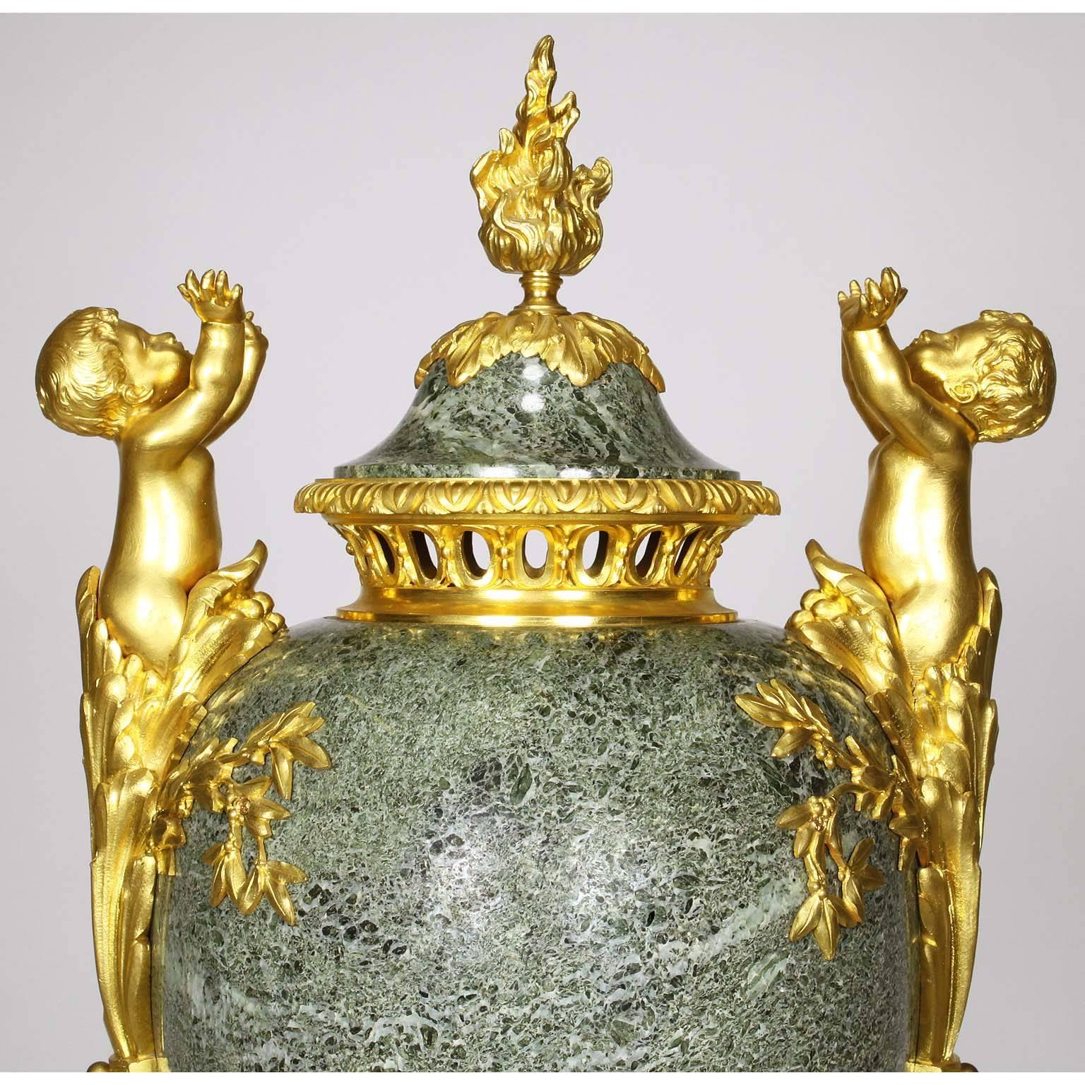 A fine French 19th-20th century Louis XVI style figural gilt bronze-mounted and Vert Maurin marble covered urn. The domed cover centred by a flambeau finial, the ovoid body flanked by a pair of Putti (children) terms with their arms raised, warming