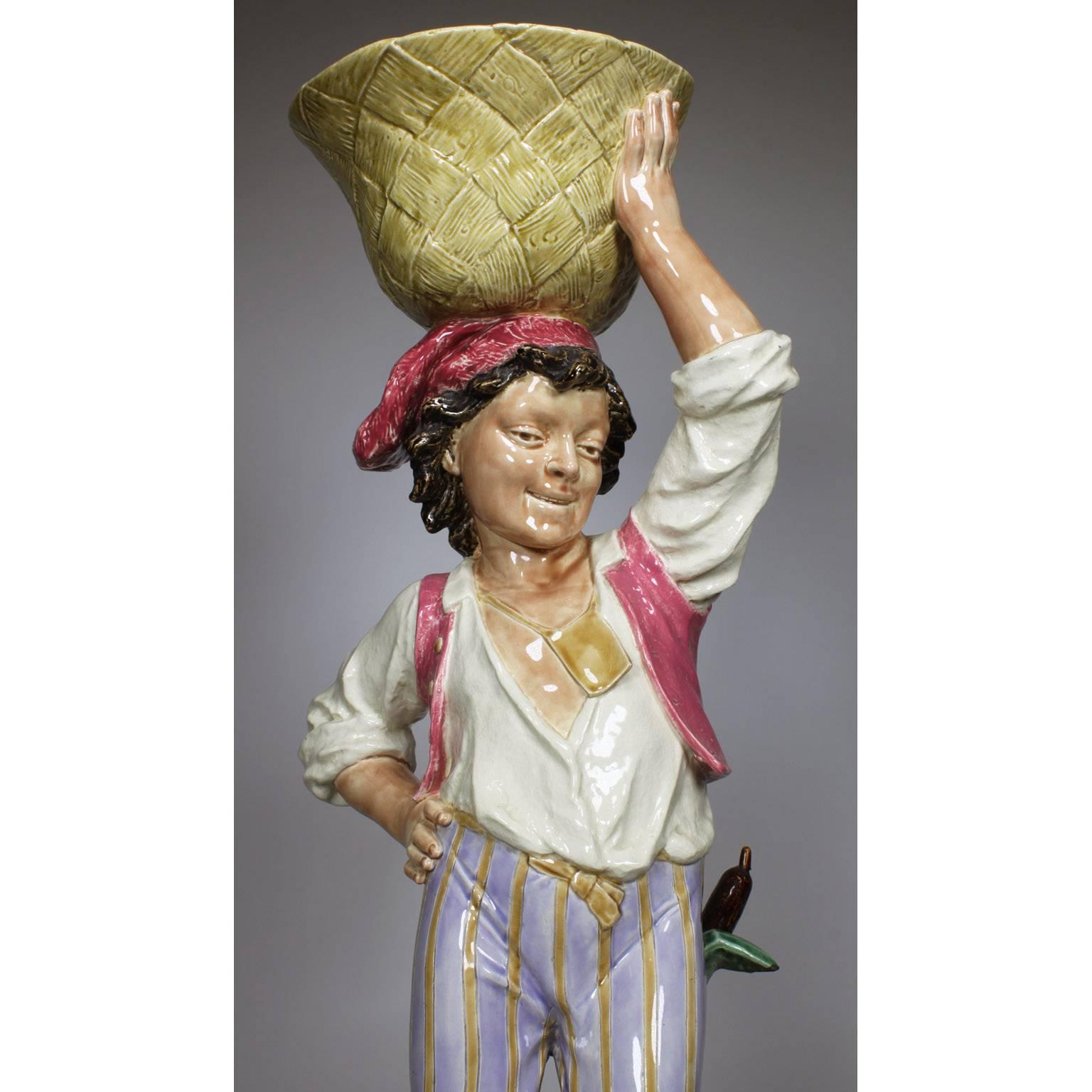 A French late 19th century Majolica figural jardinière (planter) modeled as a young Neapolitan vintner boy balancing a weaved basket over his head, standing on the back of a tortoise on a rocky base amongst bulrushes. Mark for Choisy-Le Roy, H.