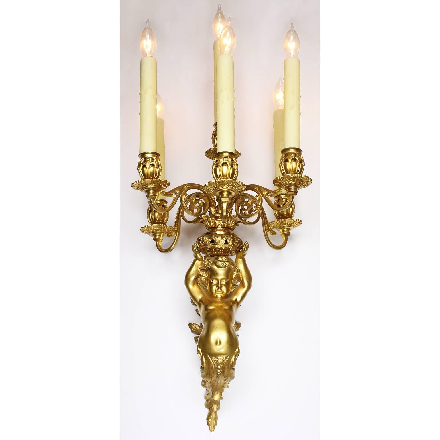 A very fine pair of French Belle Époque Louis XV style gilt bronze figural six-light wall sconces, each with a figure of a putto (child) with his arms raised holding a candelabrum, Paris, circa 1900.

Overall height (top of light bulbs) 28 1/4