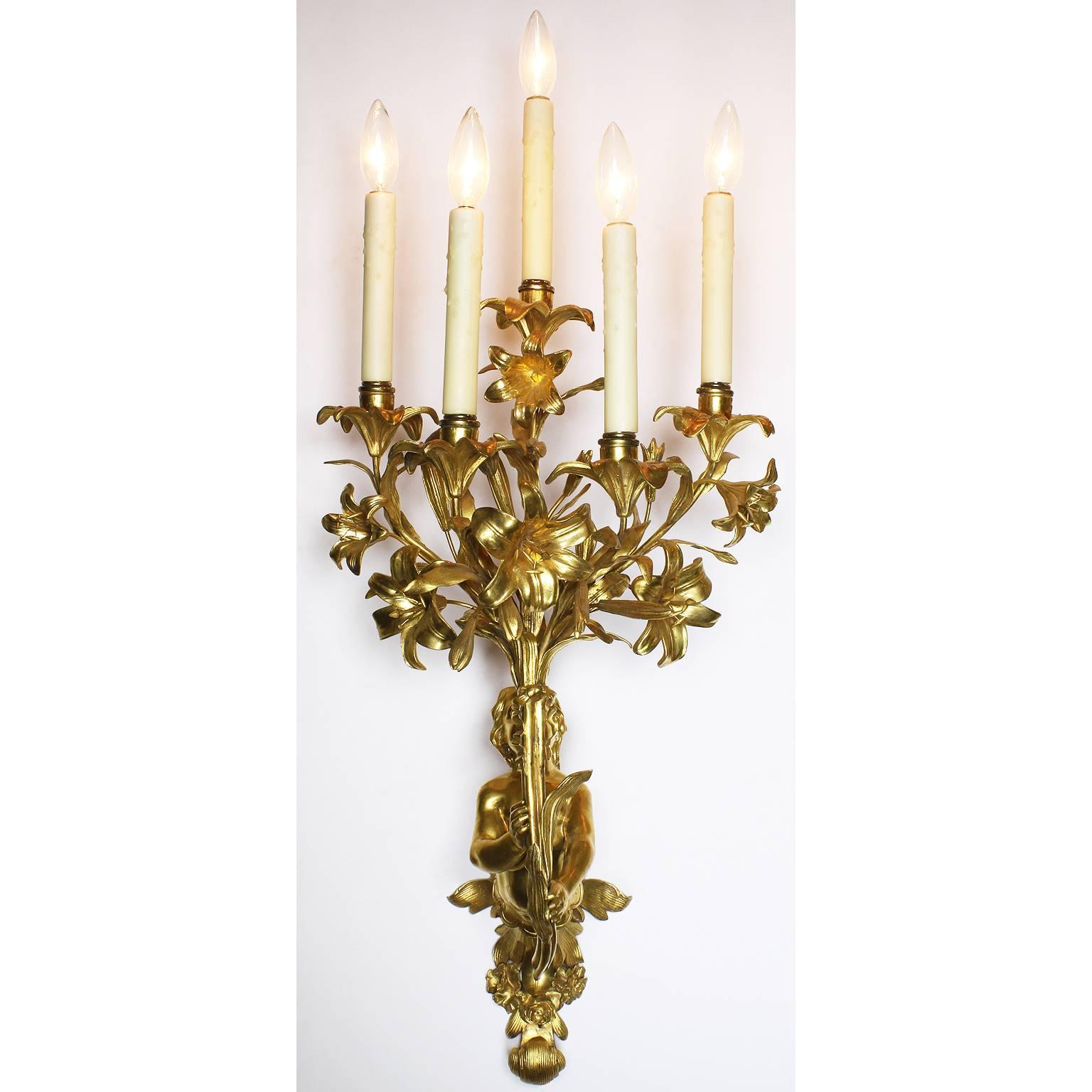 A very fine and charming pair of French 19th century neoclassical style figural gilt-bronze five-light wall sconces. Each wall light depicting a putto with his torso leaning forward and holding holding on an ornate floral candelabrum (Now