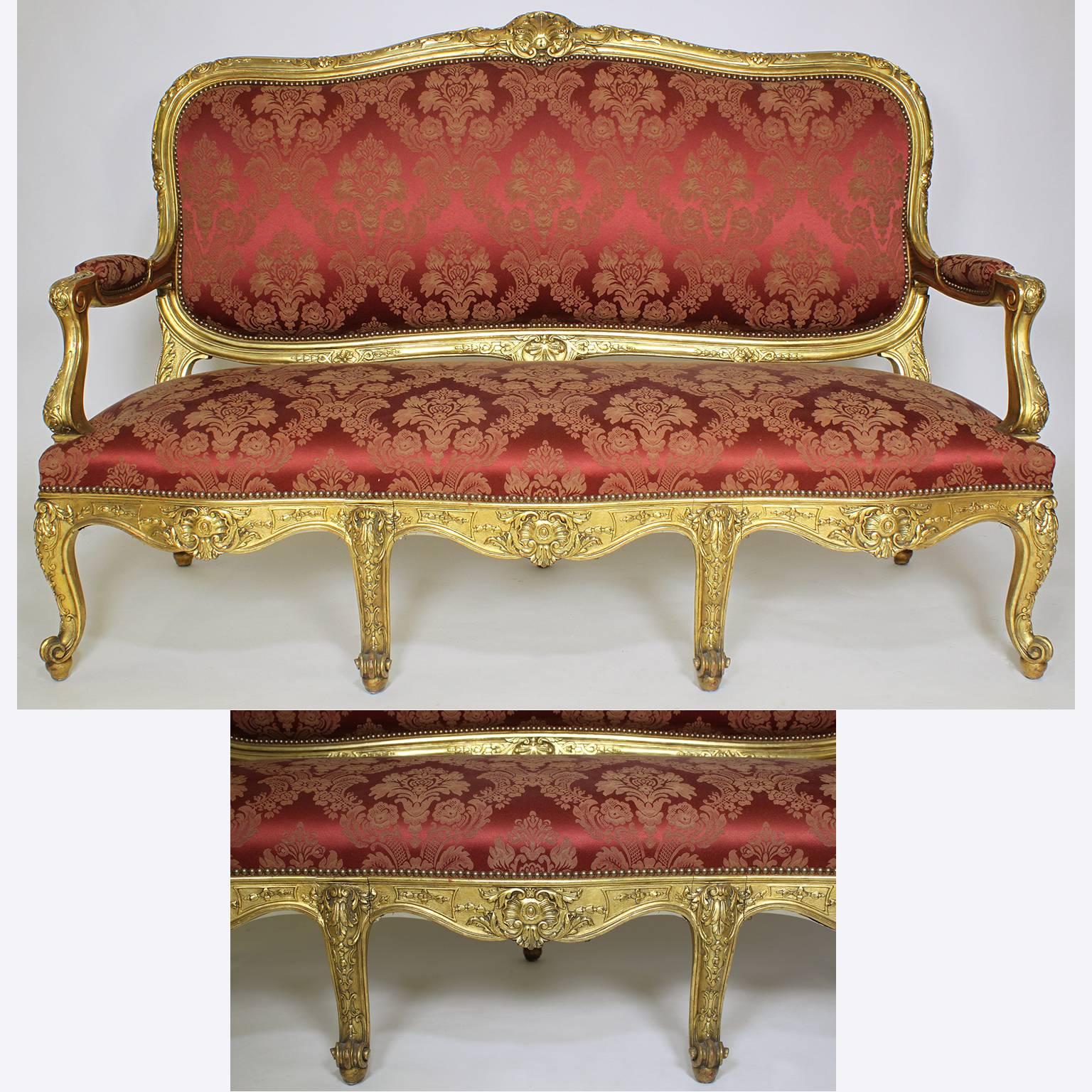 A fine French 19th century Louis XV style giltwood carved three piece salon suite, comprising of a canapé (Settee) and two fauteuils à la reine (Armchairs), all recently re-upholstered and with original gilt, Paris, circa 1890.

Measures: Settee