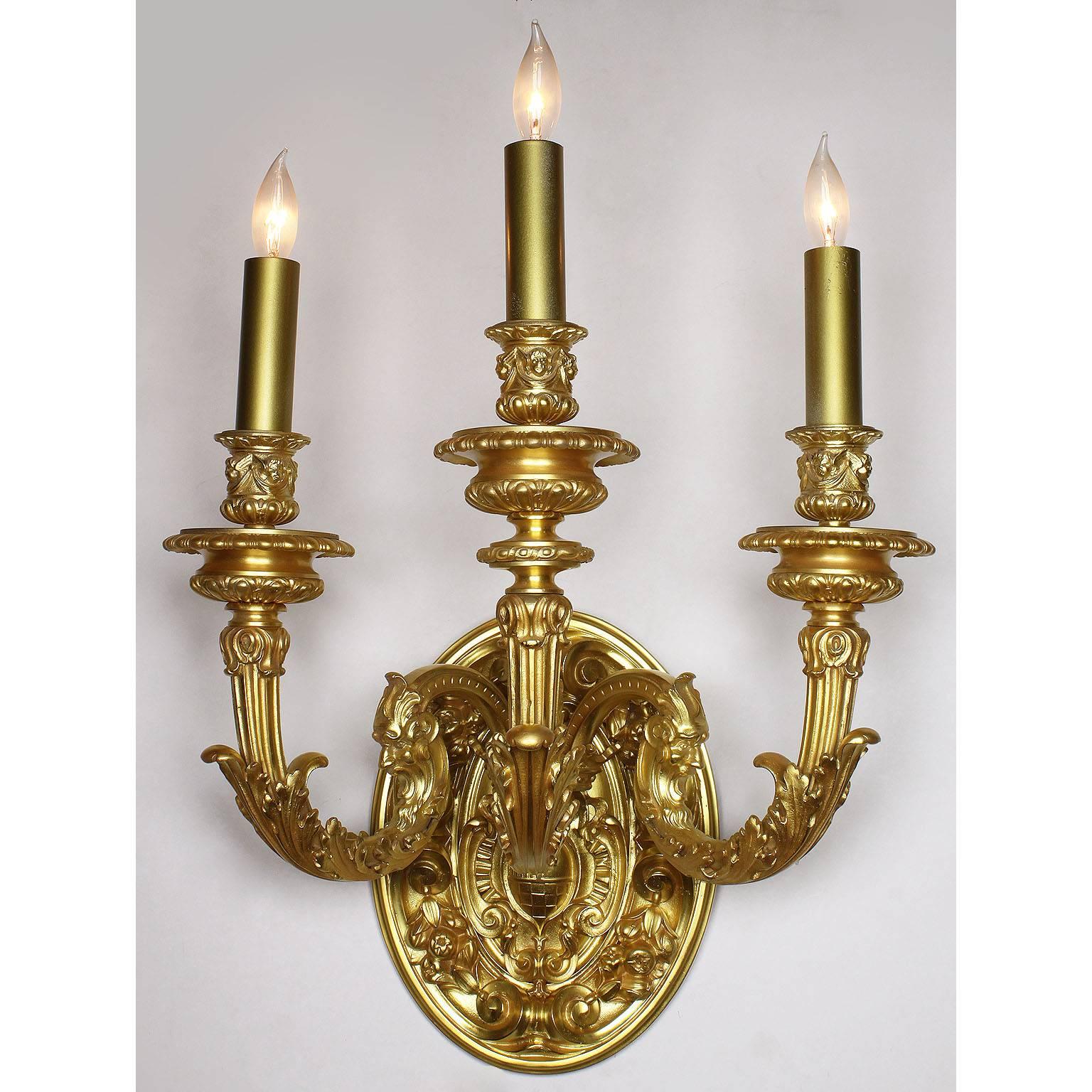 The Spelling Manor's dining-room wall-lights. A very fine pair of French 20th century Louis XV style gilt bronze figural three-light wall sconces, each with a circular coat-of-arms backplate centered with a Royal shield and relief details of fruits,