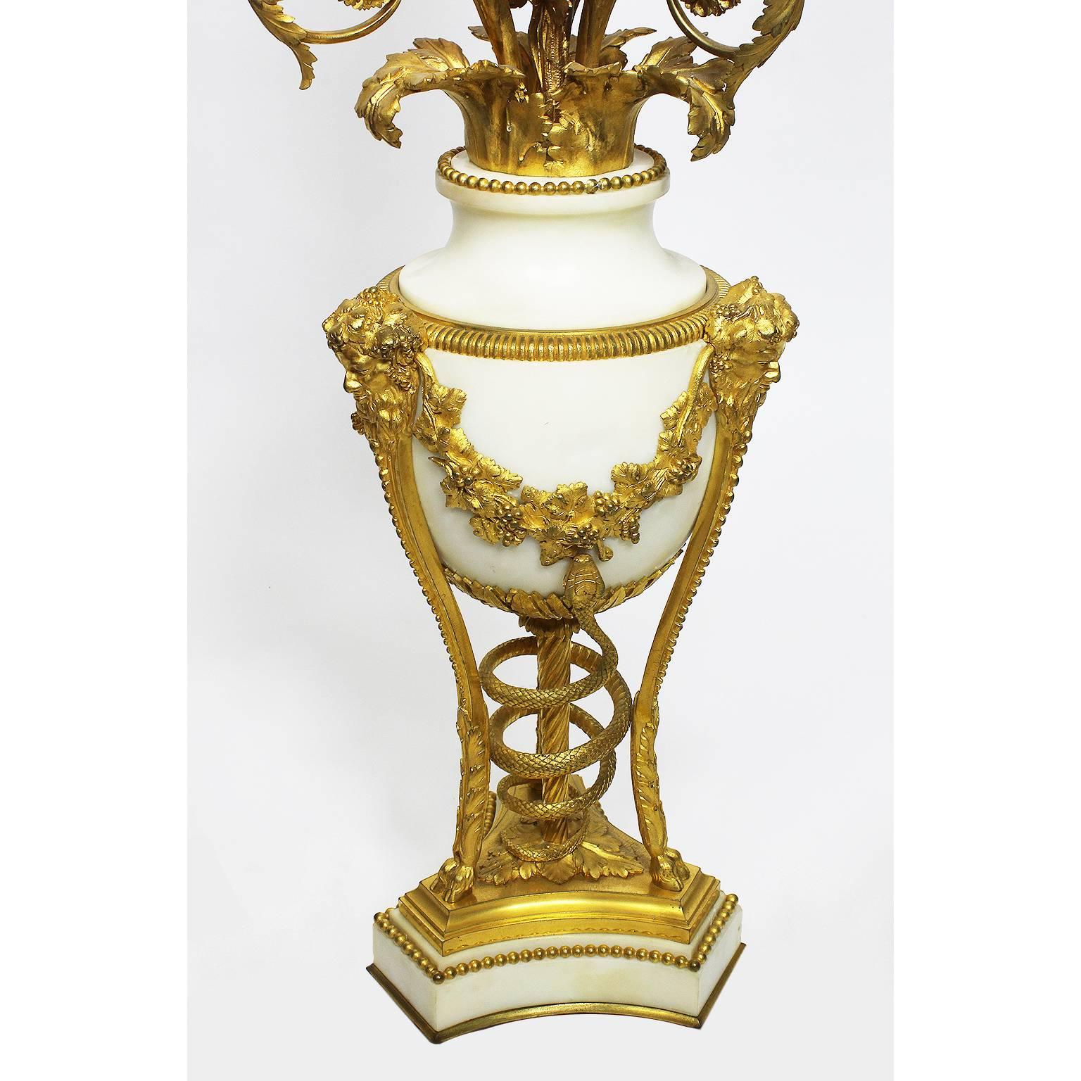 Alfred Emmanuel Louis Beurdeley (French, 1847-1919) A very fine pair of French 19th century Louis XVI style ormolu-mounted and white marble three-light candelabra (now electrified), each raised on tri-form cloven hoof topped feet below Bacchic
