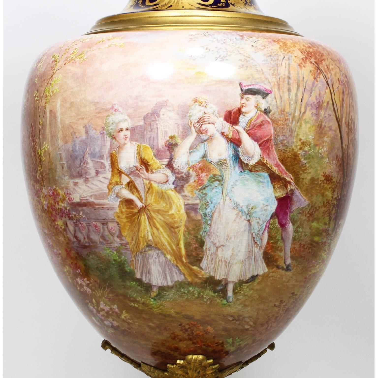 A fine French 19th century Napoleon III Sèvres style porcelain and ormolu-mounted covered urn, the 360 degree painted urn centered with an 18th century romantic scene of two ladies and a gentleman playing blindman's bluff, the rear with scenes of