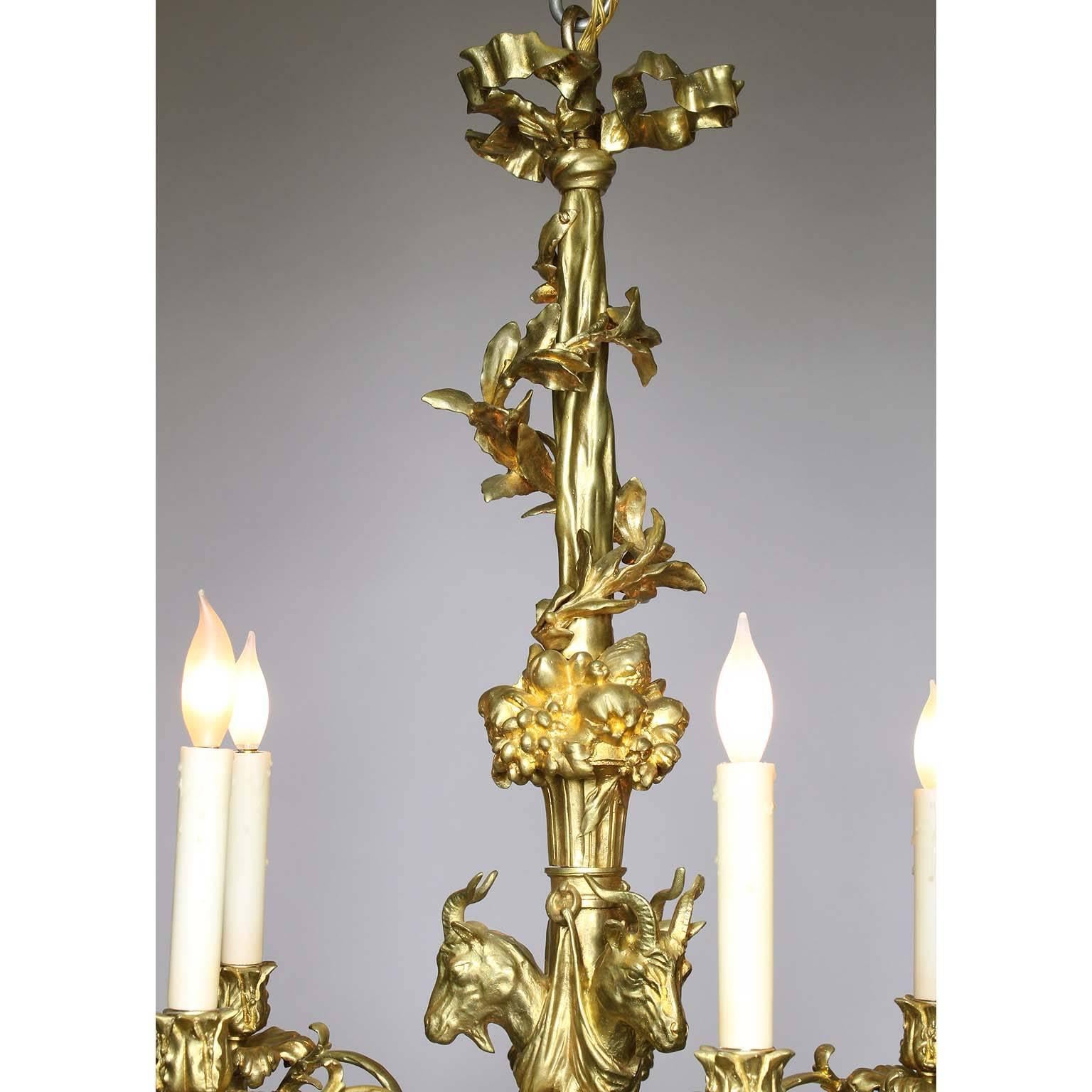 A French 19th century Louis XV style gilt bronze six-light figural chandelier. The elongated gilt bronze frame with six scrolled candle-arms (now electrified) surmounted with ribbons, vines, three ram-heads, rosettes, fruits, tassels and ending with