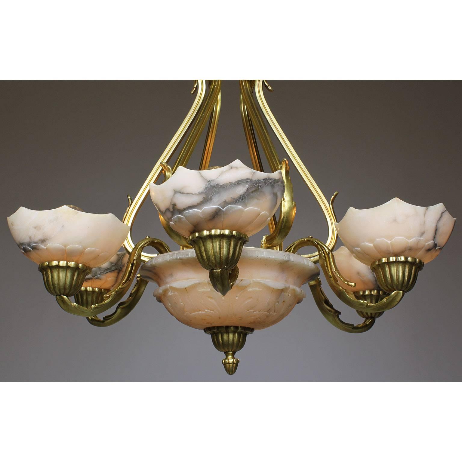 A French early 20th century Art Deco gilt bronze and carved veined alabaster seven-light chandelier. The carved circular veined alabaster plafonnier surmounted with six scrolled arms, each with carved alabaster cup-shades, all suspended with six