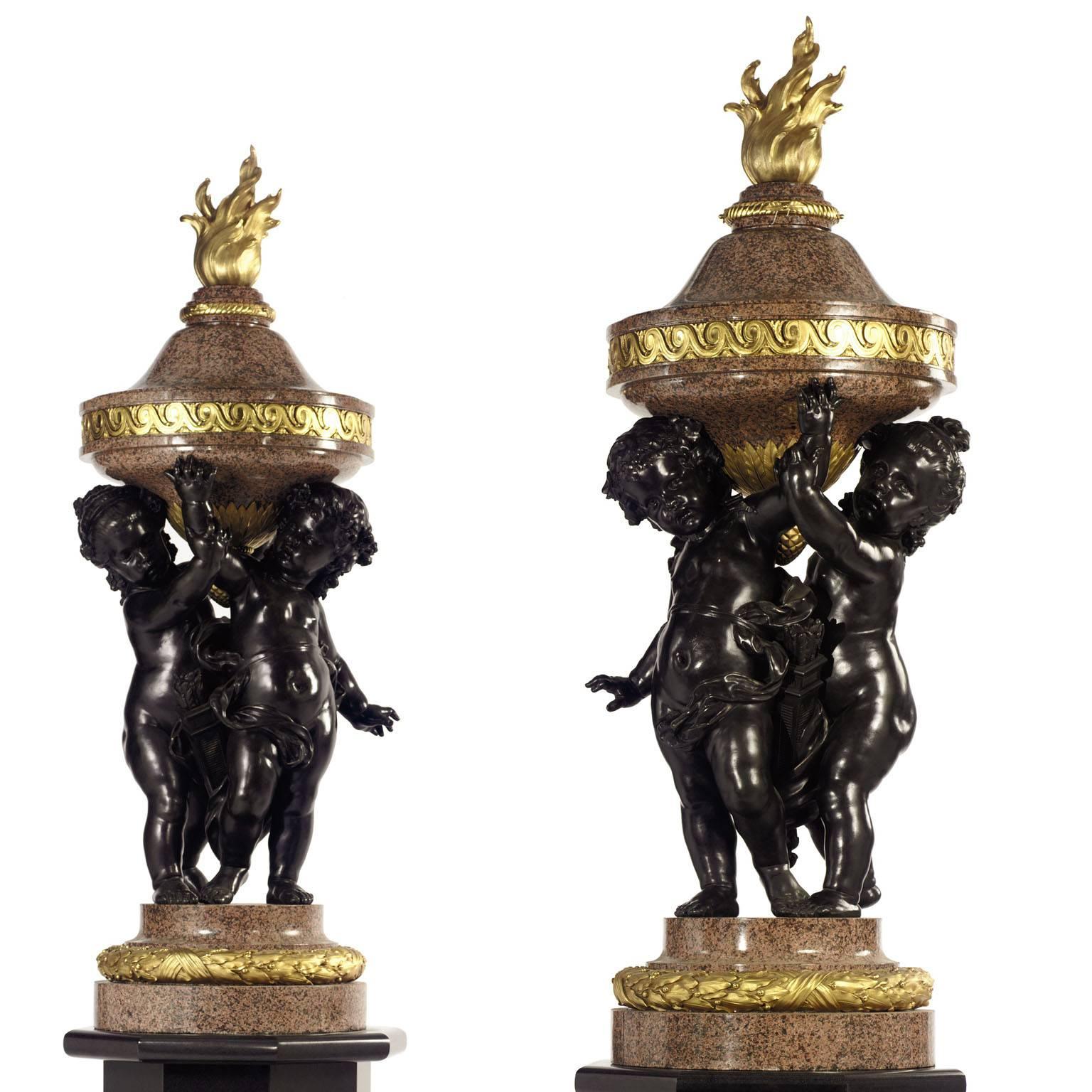 Monumental pair of French 19th century figural gilt and patinated bronze Rosso Granite marble Flambeaux Urns Torcheres, each depicting a pair of allegorical Putti (Children) holding a flaming urn, attributed to René Rozet (French, 1858-1939). Each