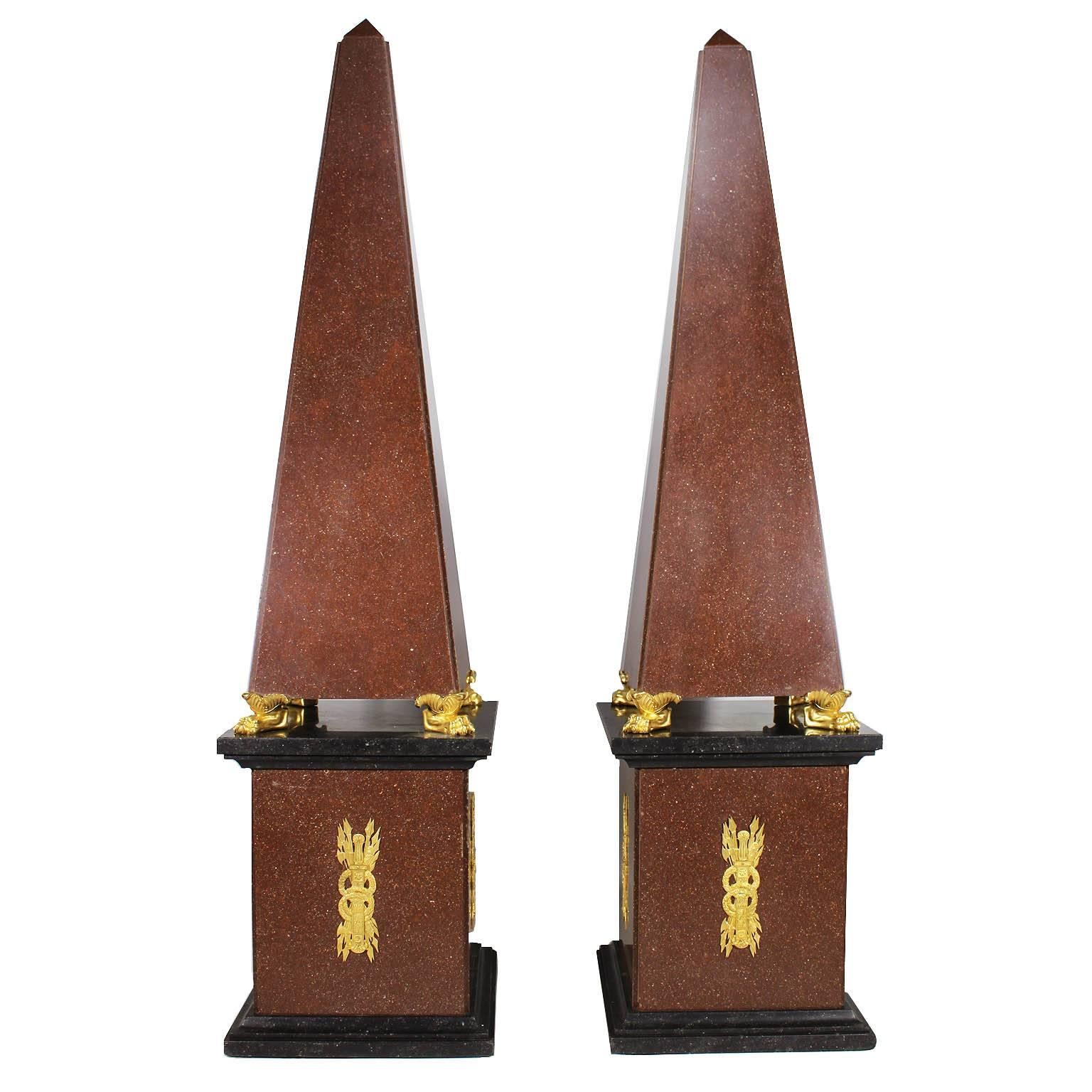 A Monumental and Fine Pair of French 19th, 20th Century Empire Style Red Porphyry-Like Granite and Gilt-Bronze (Ormolu) Mounted Obelisks on Four Gilt-Bronze Lion Paws both resting on conforming porphyry and black slate plinths surmounted with