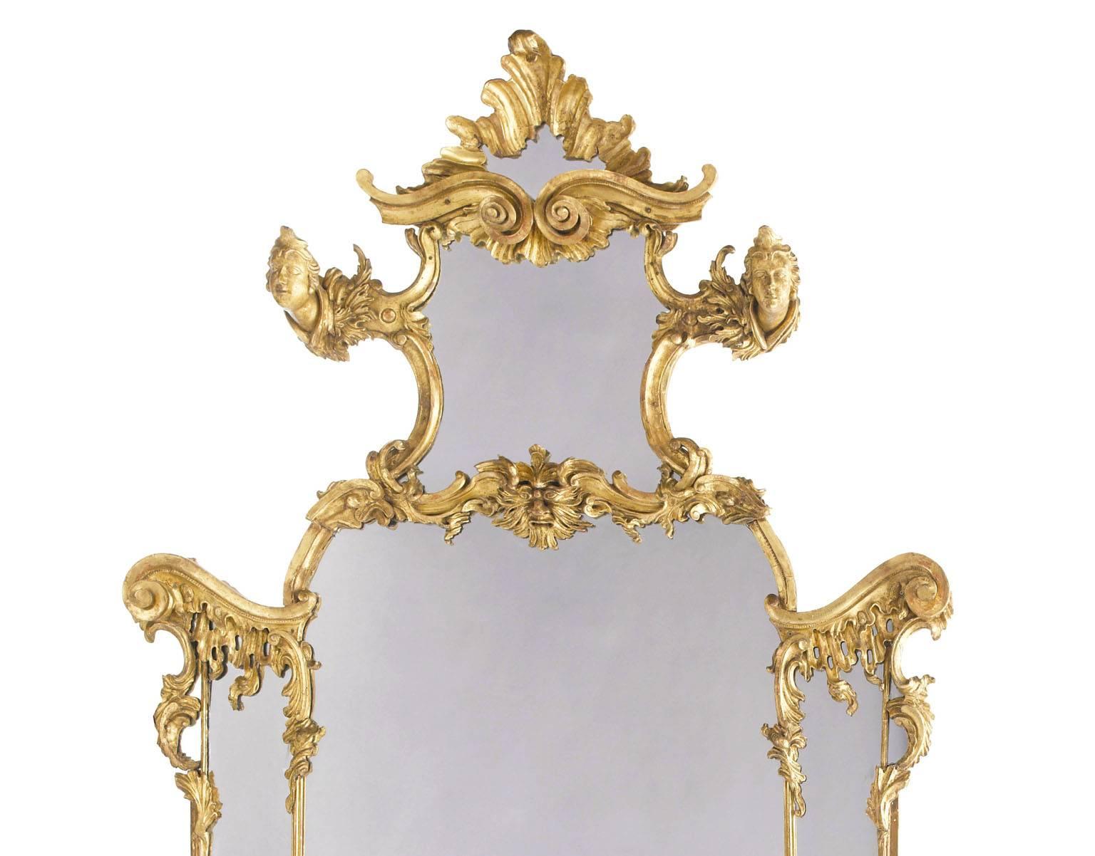 Très beau miroir figuratif en bois doré sculpté rococo italien du XIXe siècle. Les plaques de miroir sectionnelles arquées sont entourées de bordures décorées de rinceaux et de feuillages entrecoupés de bustes et de masques, et reposent sur des