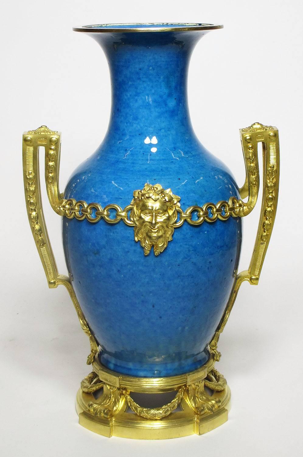 Très belle et impressionnante paire de vases de style Louis XVI français du XIXe siècle, montés en bronze émaillé bleu, avec des masques allégoriques, des anneaux et des couronnes. La porcelaine est probablement chinoise du XVIIIe siècle, période