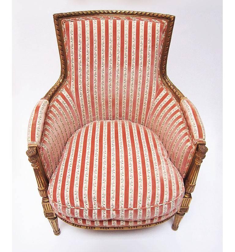 A fine pair of French 19th-20th century Louis XVI style giltwood carved bergères, each with a recent upholstered back, sides and loose cushion seat in a striped and floral velvet fabric, Paris, circa 1900.

Height: 37 inches (94 cm).
Width: 28