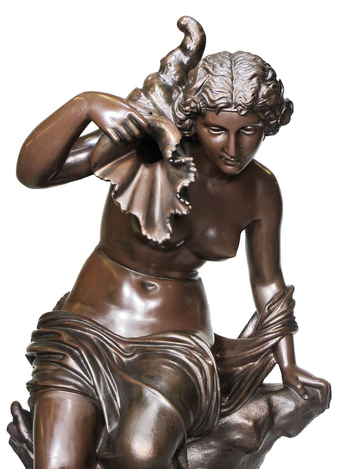 Feine und große französische Brunnenfigur aus Gusseisen aus dem 19. Jahrhundert in Form eines nackten Mädchens, das auf einem Felsvorsprung sitzt und ein Füllhorn in der erhobenen rechten Hand hält, von J.J. Ducel. Gegossen und signiert 