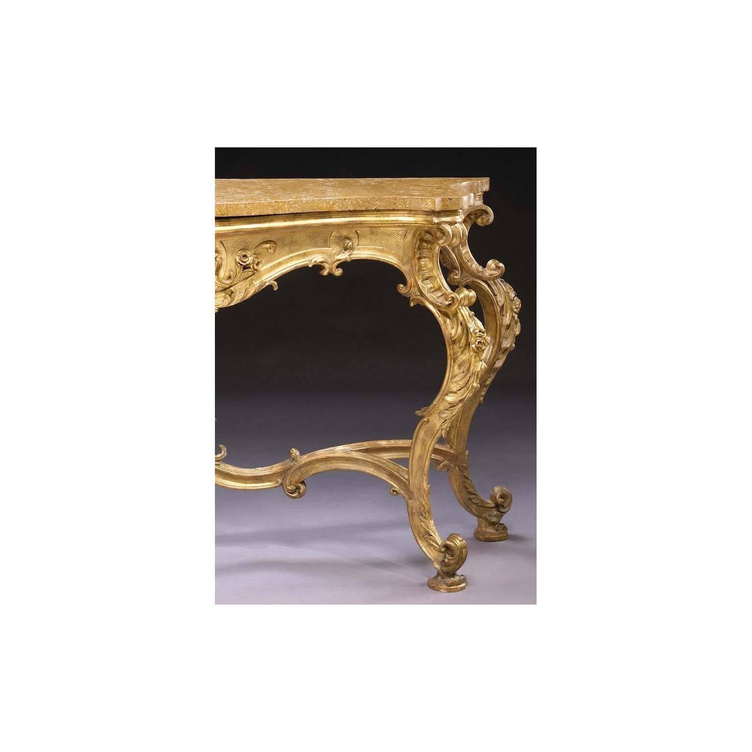 A very fine and palatial Italian 18th century Rococo style giltwood carved console table with a castracane marble top of serpentine outline, the frieze with a pierced cartouche decorated with flowers and foliate, raised on cabriolet legs with