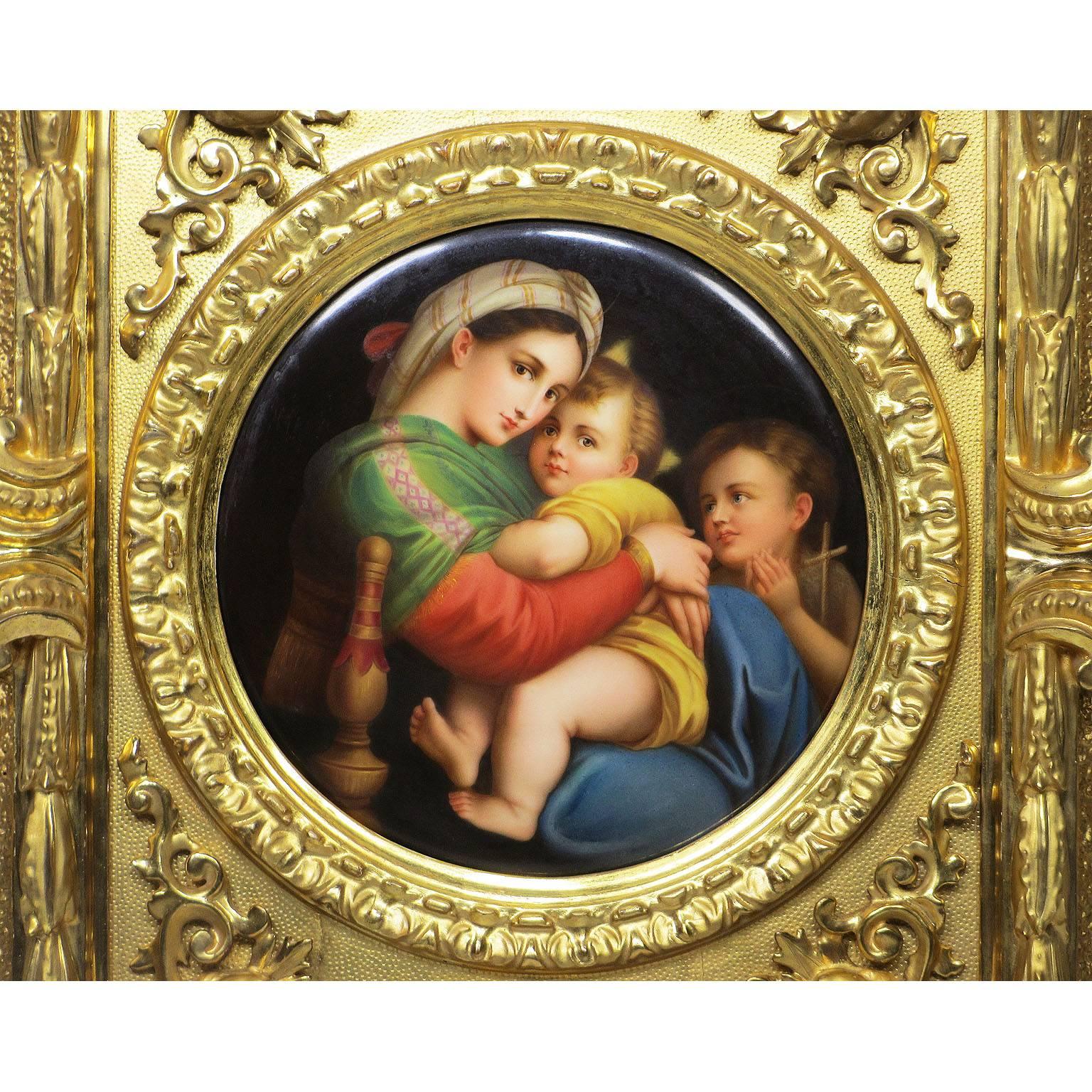 A very fine German 19th century circular porcelain plaque painting of La Madonna della Sedia after Raphael Sanzio (1483-1520), depicting a seated Madonna and child next to a child Saint John the Baptist, within a giltwood carved figural frame, the