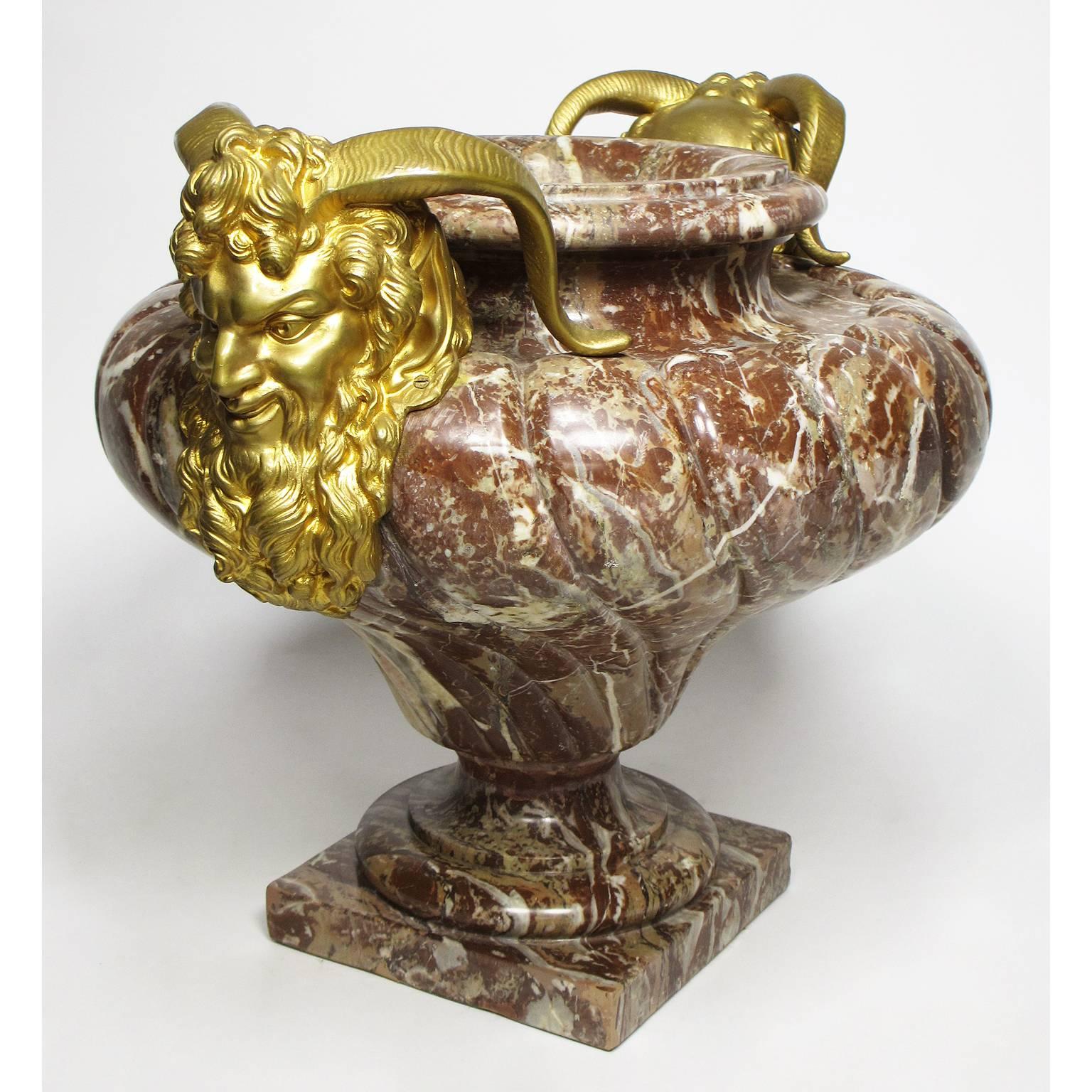 A very fine and French 19th century Louis XV style carved rouge-royal marble and figural gilt bronze-mounted planter-urn, surmounted with a pair of gilt-bronze masks of a Satyr, circa Paris, 1880.

Height: 18 inches (45.7 cm).
Width: 22 3/4