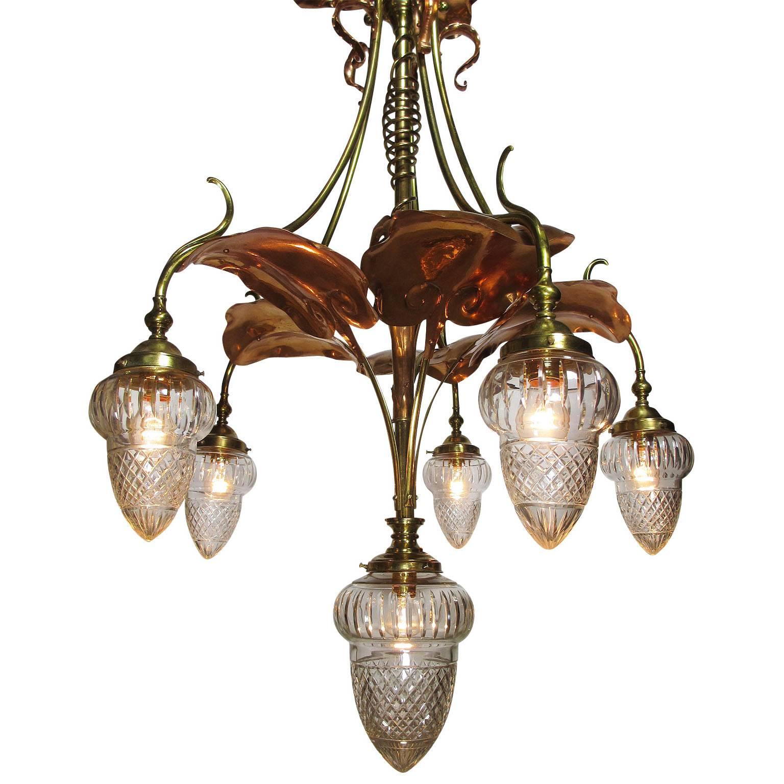 A large fine and rare English Art-Nouveau arts and crafts movement, brass and copper six-light chandelier, the central support pole having a spiraling brass ornament surmounted with applied copper lily pad leaves, with six brass drop-lights with