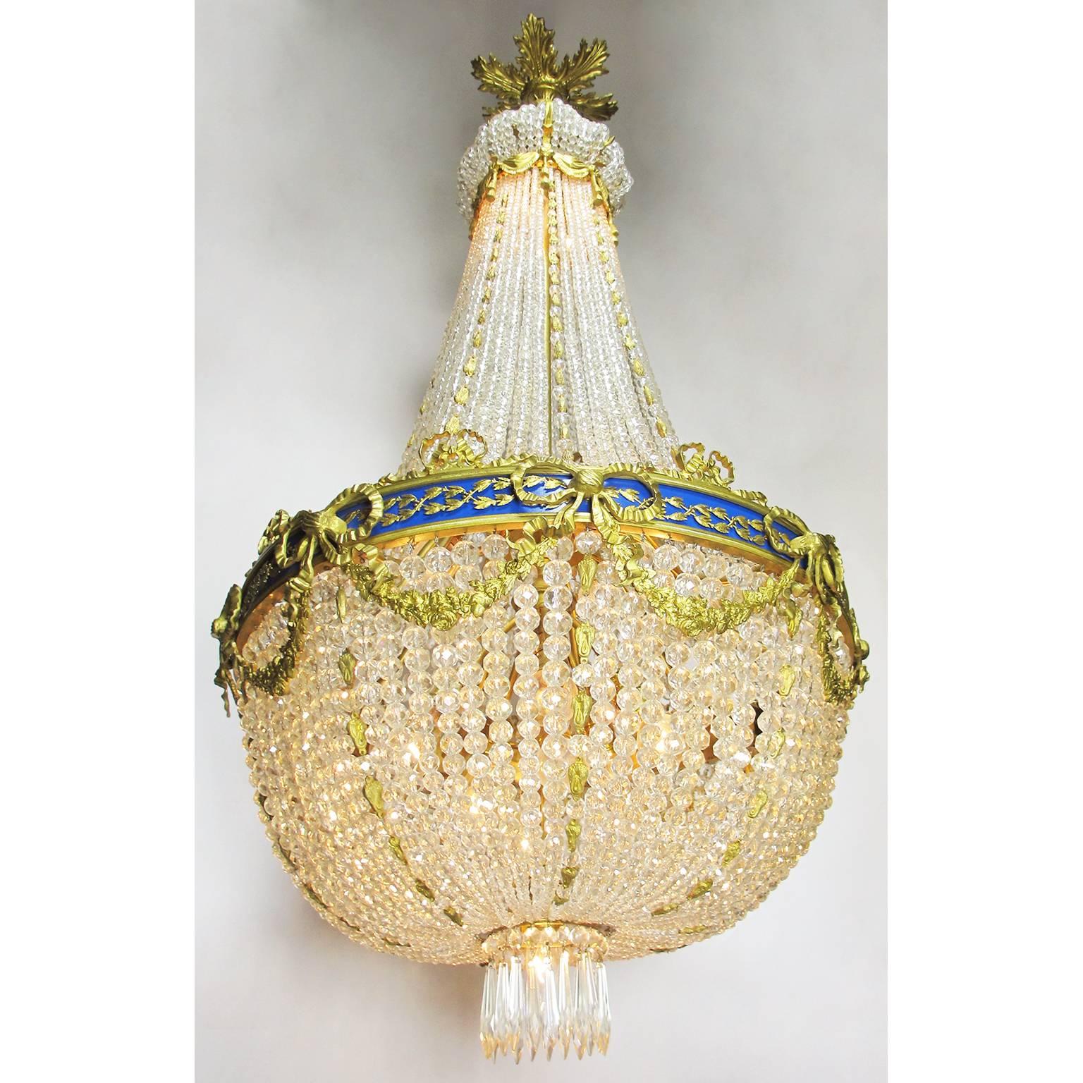 A fine and large French Empire style 19th-20th century gilt bronze and cut-glass prisms cascade fourteen-light chandelier. The basket shaped beaded glass body surmounted with gilt bronze strands, the center gilt-bronze rim with a Royal Blue