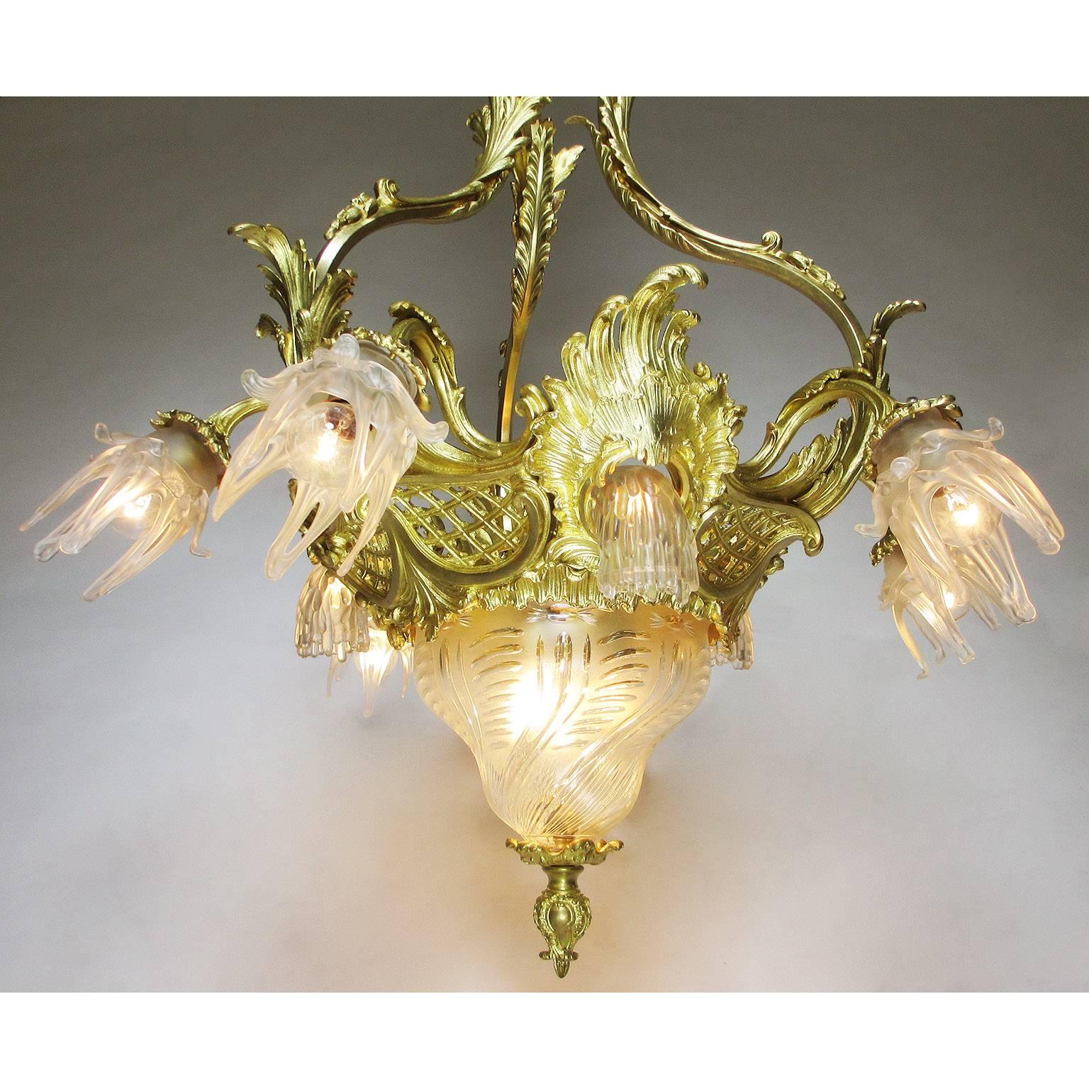 A very fine French Belle Époque gilt bronze and molded cut-glass thirteen-light chandelier, the circular shaped frame surmounted with an ovoid and spiral pear-shaped molded and frosted cut-glass plafonnier with three inside lights, the rim with