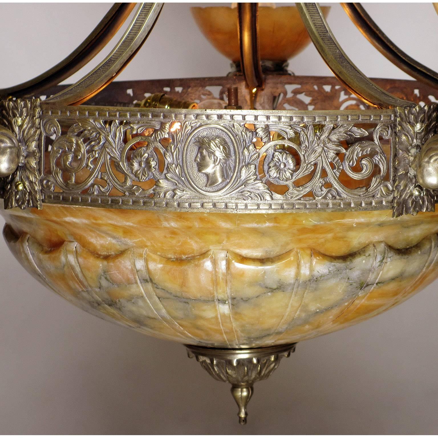 An Italian early 20th century Art Deco silvered bronze and carved caramel color alabaster five-arm and eight-light figural chandelier. The intricate pierced floral rim with profile busts of Julius Ceasar and surmounted with five cornucopia