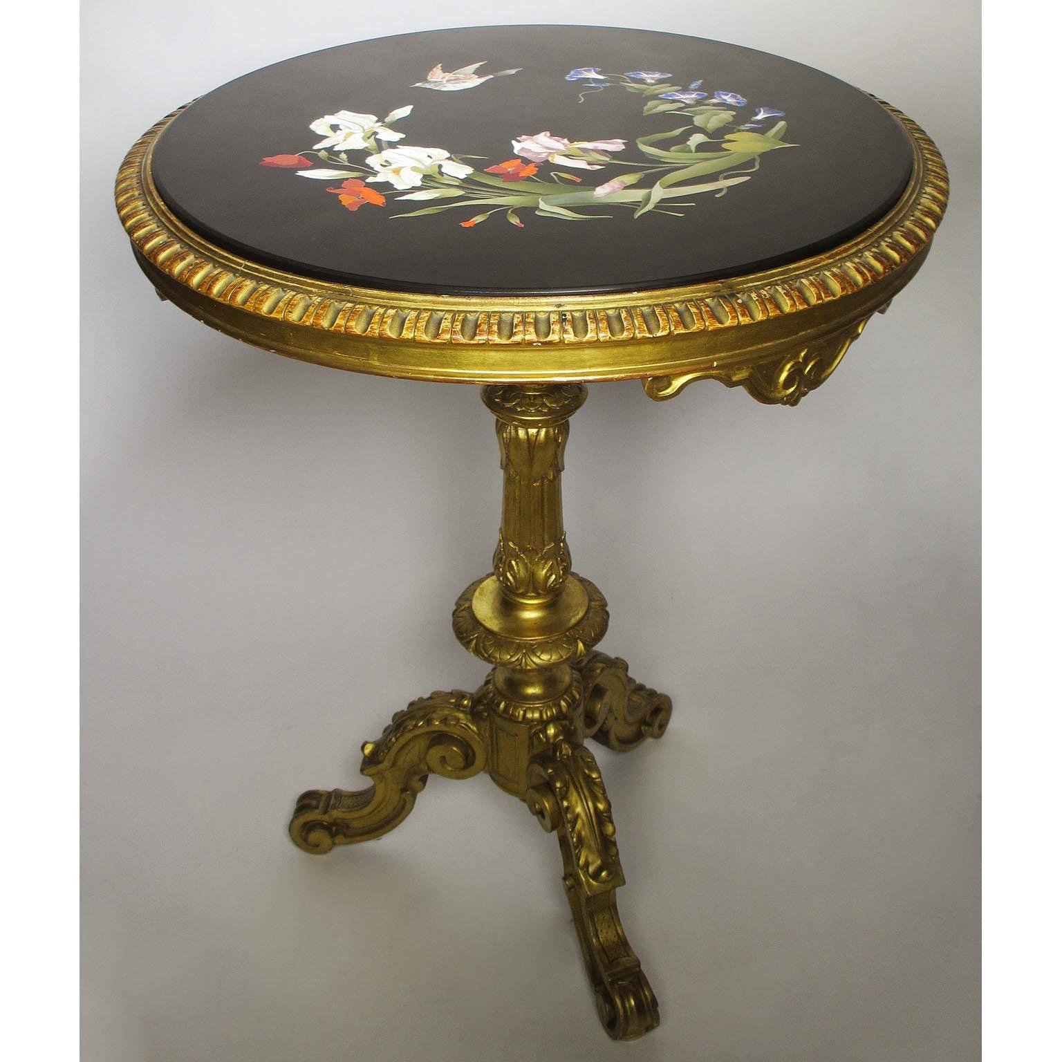 Ein sehr feiner italienischer Pietra-Dura-Tisch mit Intarsien aus dem 19. Jahrhundert, der auf einem geschnitzten Sockel aus vergoldetem Holz steht. Die kreisförmige Pietra-Dura-Intarsienplatte zeigt einen Blumenstrauß mit Lilien, Paradiesvögeln,