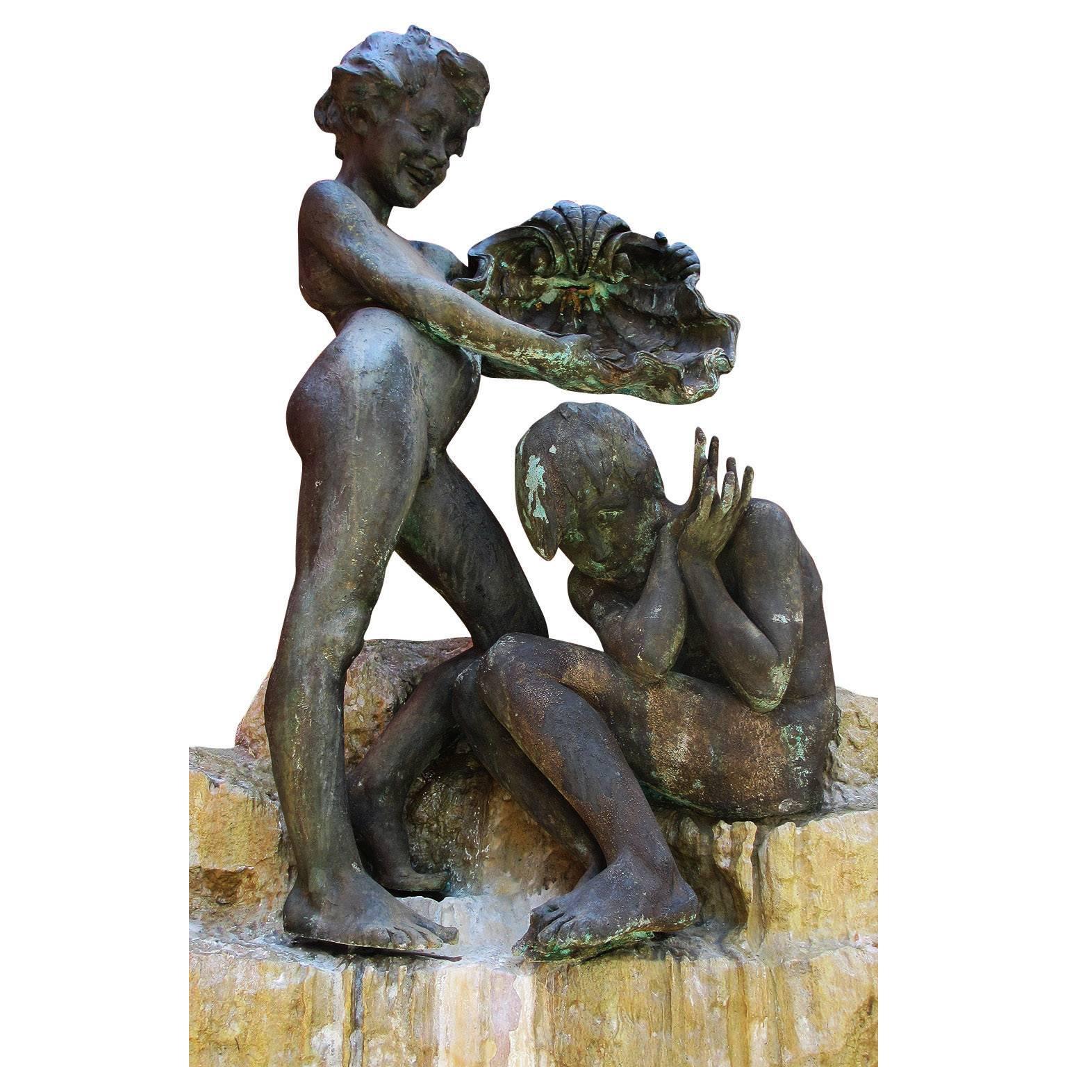 A charming whimsical mid-20th century figural bronze and carved stone sculpture/fountain depicting two young boys, one standing holding a large conch over a sitting and crouching one below, both above a stepped stone base with carvings of lily pods.