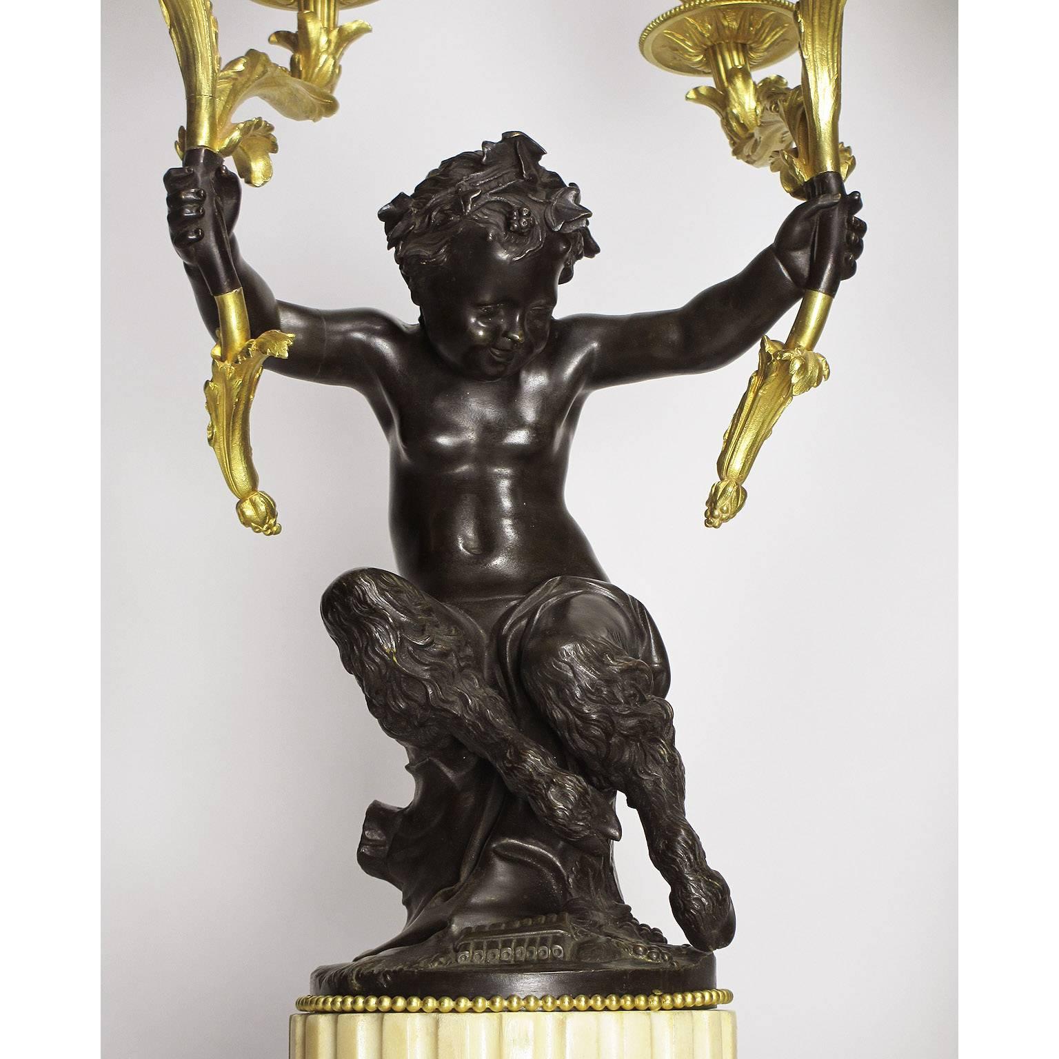 A fine pair of French 19th century gilt bronze and patinated bronze figural four-light candelabra, each modeled as a baby Bacchus, in the form of a child faun, seated on tree trunk and crowned with a vine, holding twin candlelight's on each arm, a