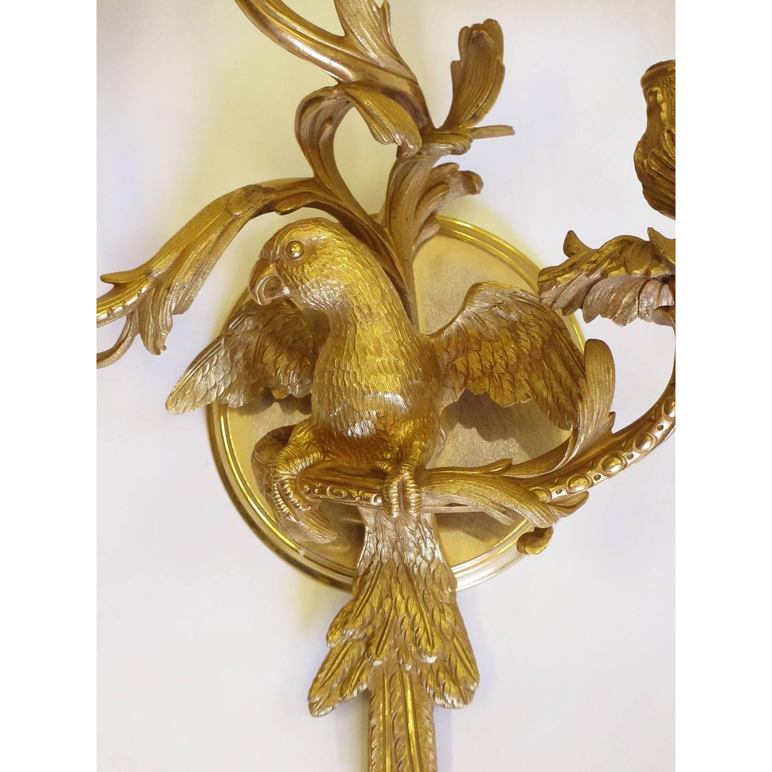 The Spelling Manor's living-room wall-lights. A fine pair of French 20th century Louis XV style gilt-bronze figural three-light wall sconces, each modeled with a center cast of a parrot, the waisted urn nozzles with lobed undersides, above foliate