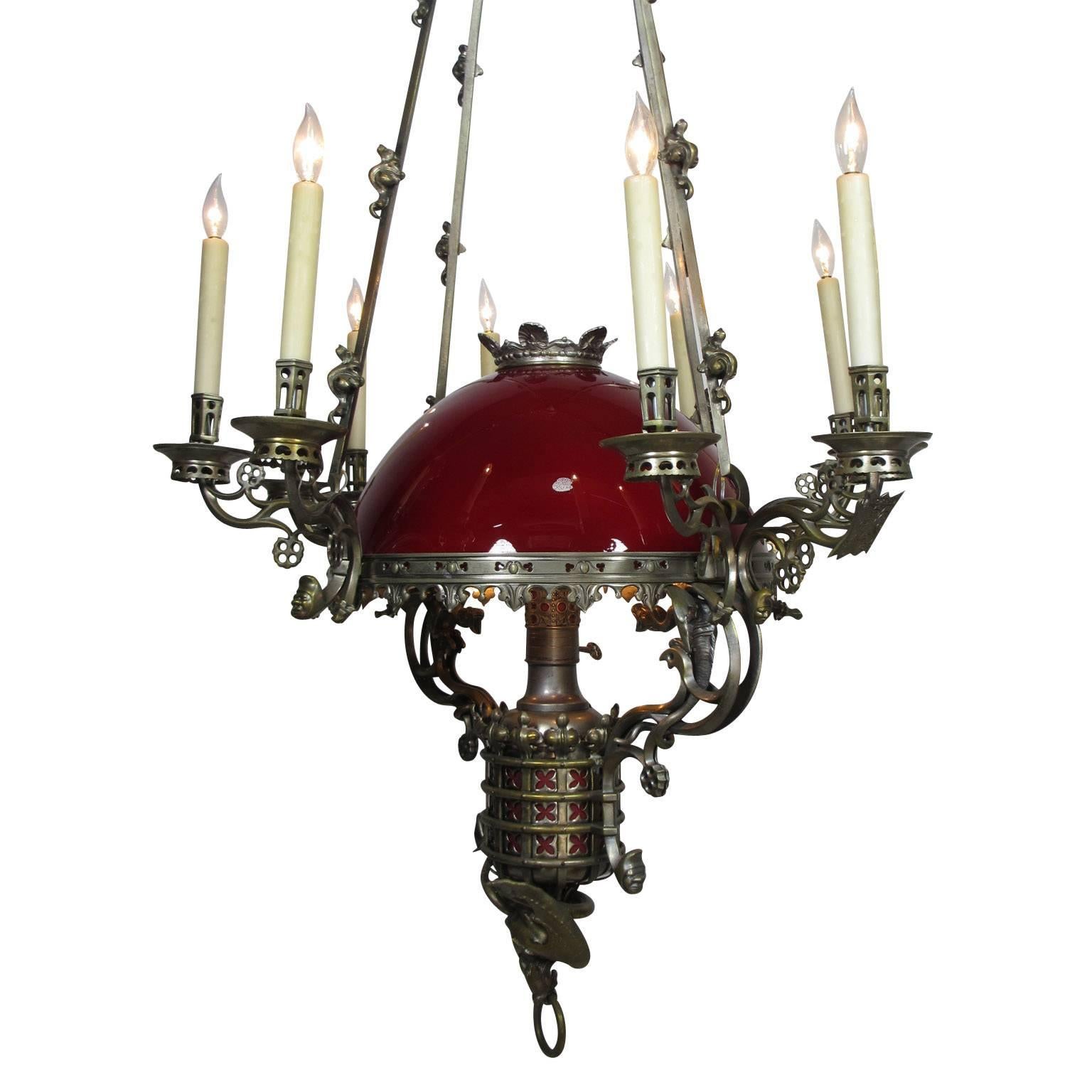 A fine and large Anglo-French 19th-20th century Gothic-revival figural silvered bronze fourteen-light oil and candle chandelier (now electrified). The elongated bronze frame crowned with its original ruby-red blown glass dome above a rim surmounted