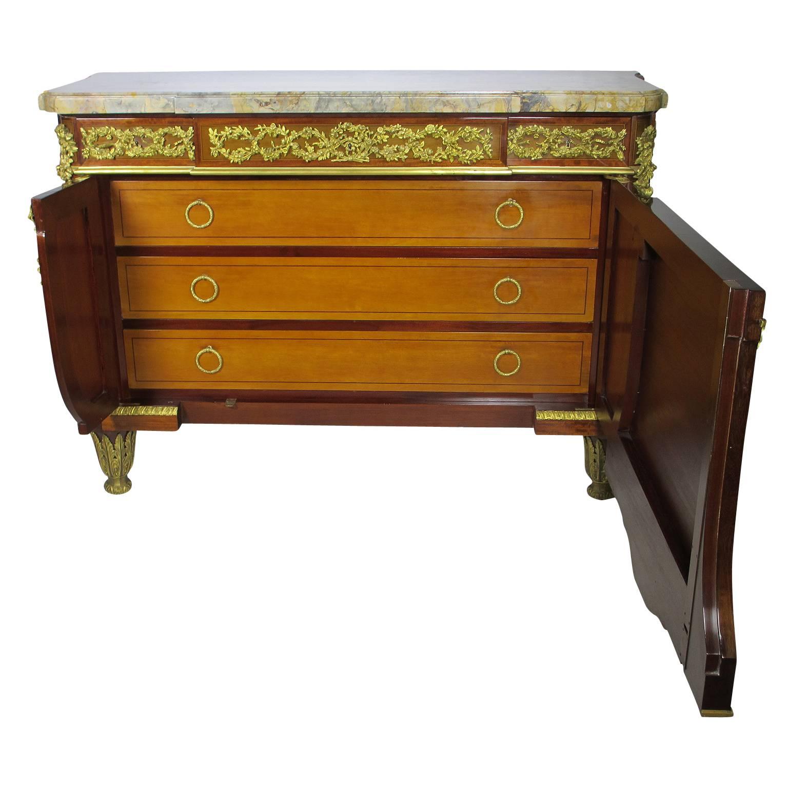 A very fine and palatial French 19th century Louis XVI style gilt bronze-mounted mahogany, satinwood, tulipwood and fruitwood marquetry and parquetry commode, after a model by Jean Henri Riesener (French, 1734-1806) fitted with three frieze drawers