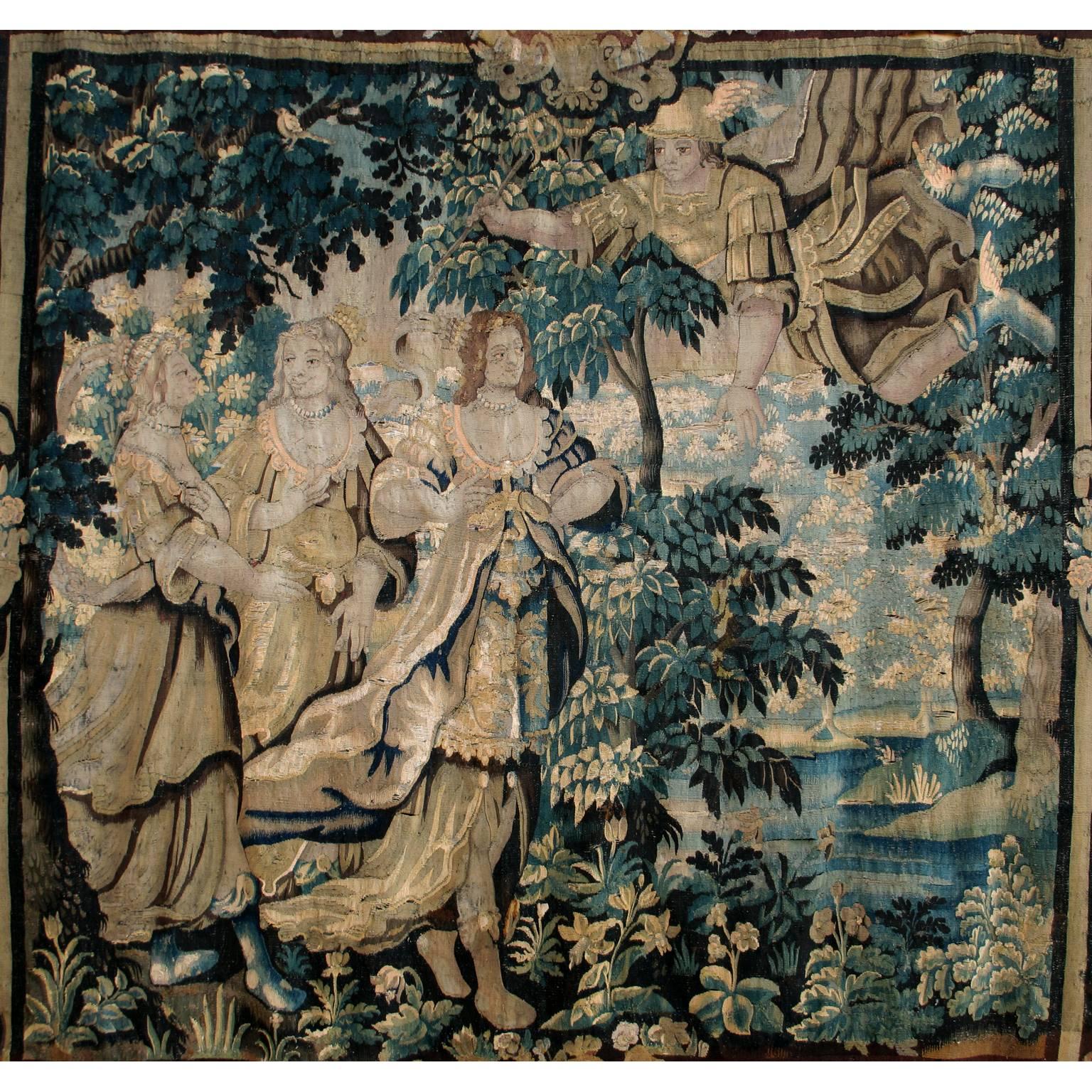A very fine baroque Franco-Flemish 18th century figural tapestry allegorical to triumph and love, depicting three maidens within a verdure background next to a shoreline, being approached by a flying archangel. The upper corners with figures of