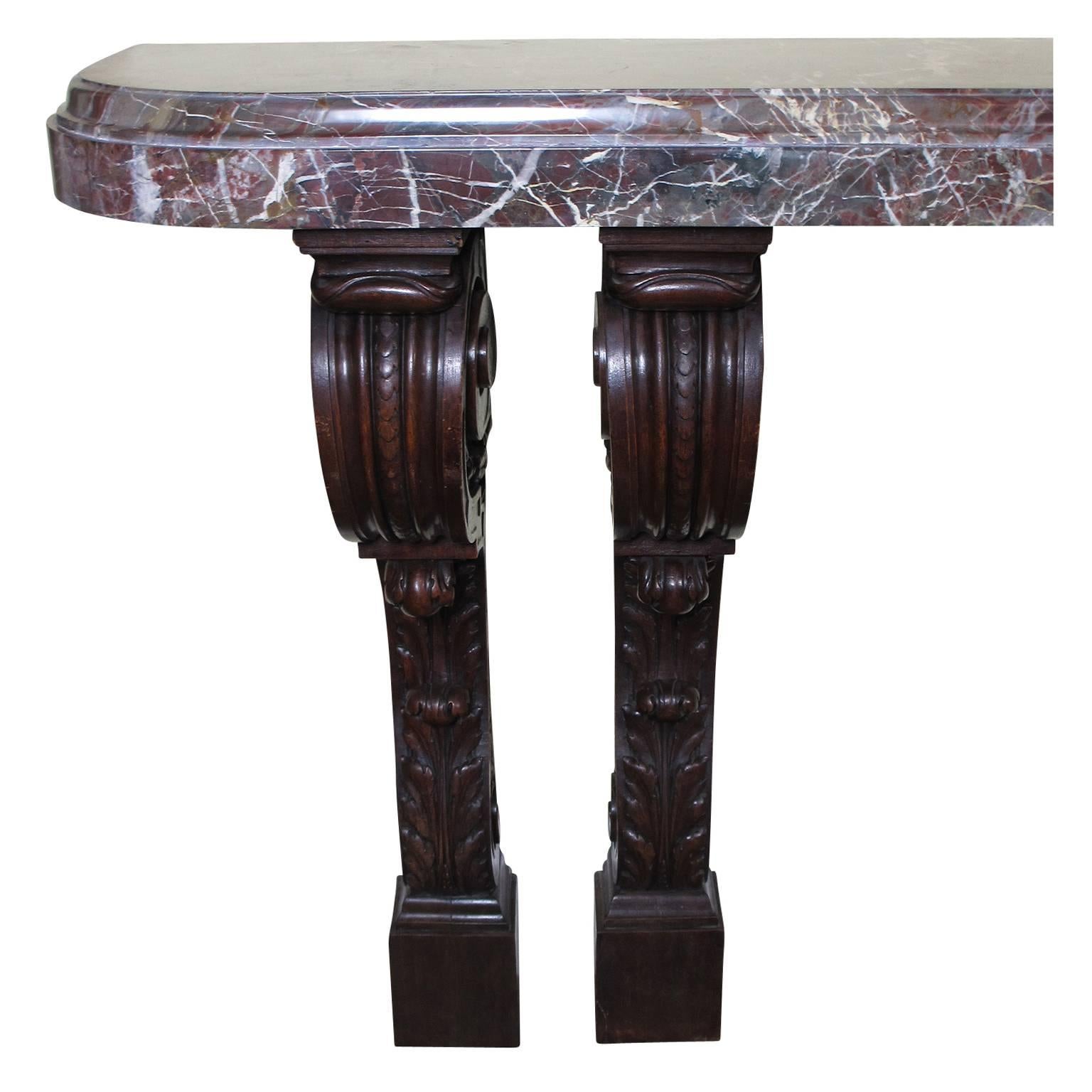 A fine and large French 19th century Louis XV style barroque carved walnut wall console table with marble top. The four individual scrolled and carved walnut pedestals support the large and 4 inch (10.2 cm) thick Italian Rosso Levanto demilune
