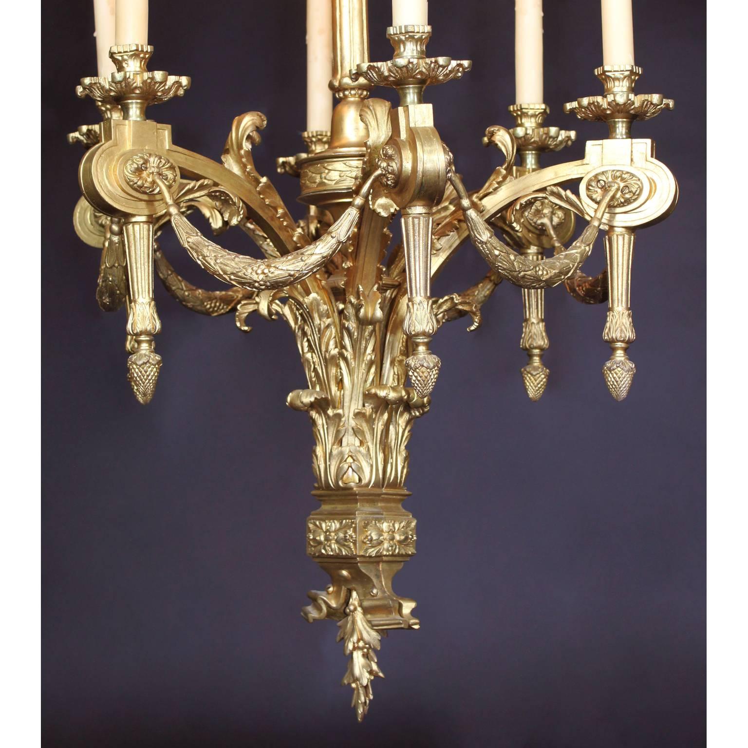 Französischer sechsflammiger Kronleuchter aus vergoldeter Bronze im Stil von Louis XV I. Jeder Kerzenarm ist mit Girlanden über einer Kartusche verbunden, die mit einer Eichel endet. Der mittlere Stiel mit einer floralen Schleife über einem Sockel