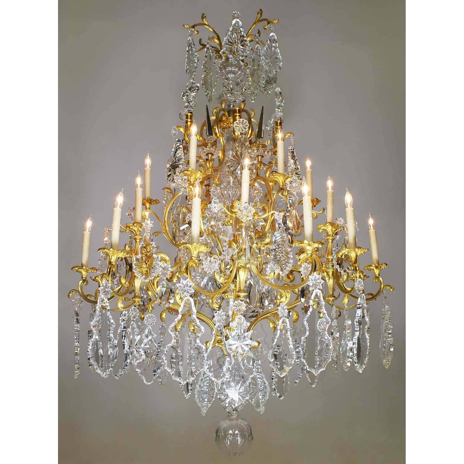 A very fine and Palatial French 19th century Louis XV Style gilt bronze, crystal and cut-glass Twenty-Four-light chandelier, probably by Baccarat. The central molded cut-glass stem surmounted with crystal obelisks, fleur de lis and cut-crystal